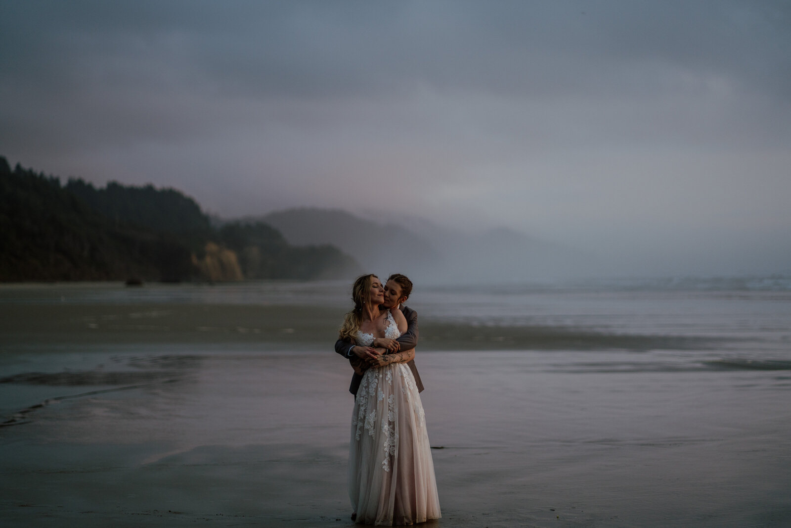 Same sex couple (brides) hugging during their Oregon Coast Elopement in Cannon Beach, Oregon