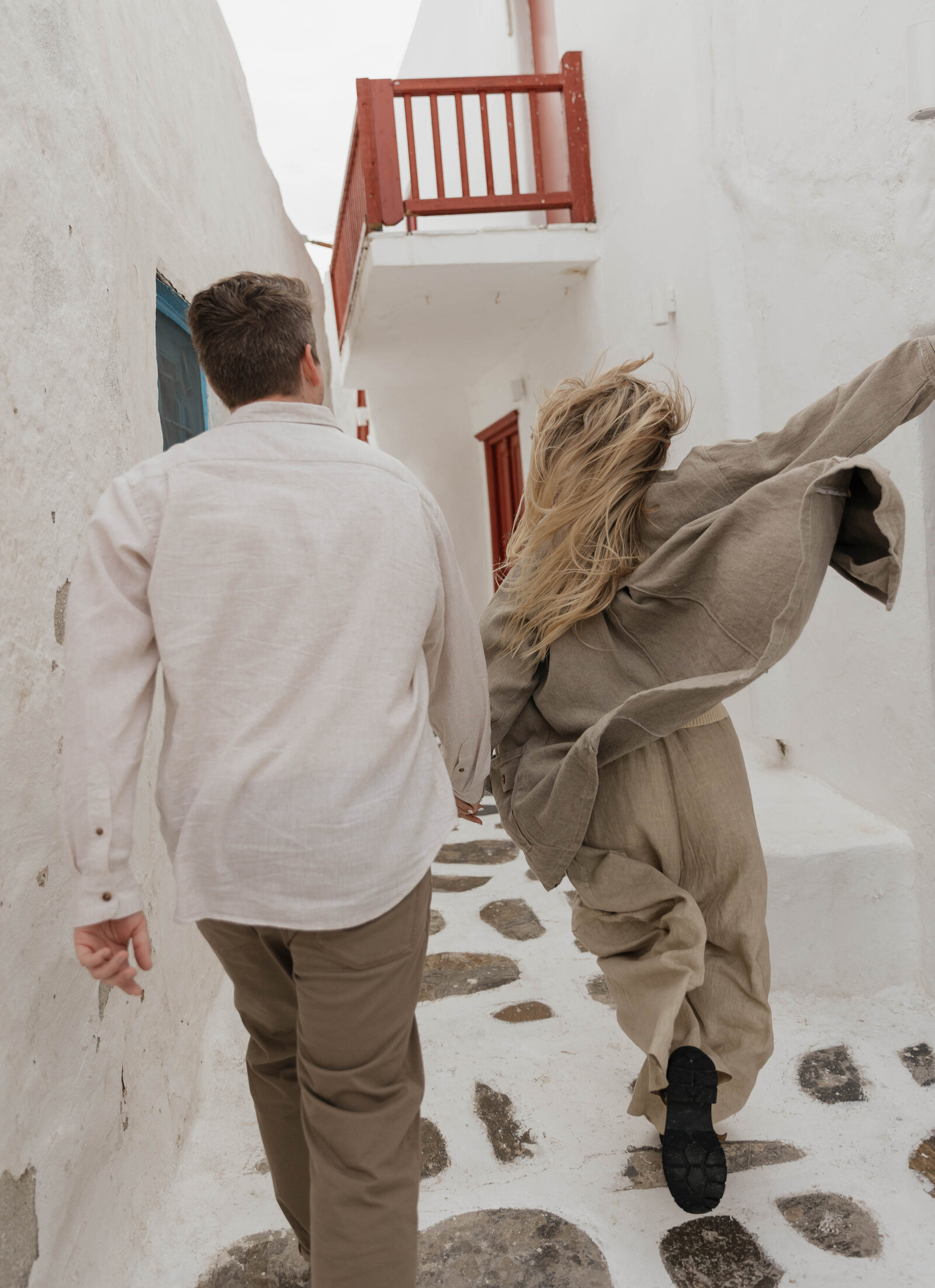 An elopement photographer captures a happy couple running through the streets of Greece.