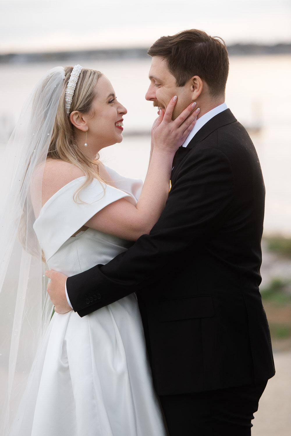 bride holds grooms face smiling