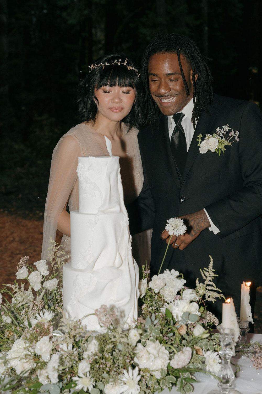 Bride and groom smiling together while cutting their wedding cake