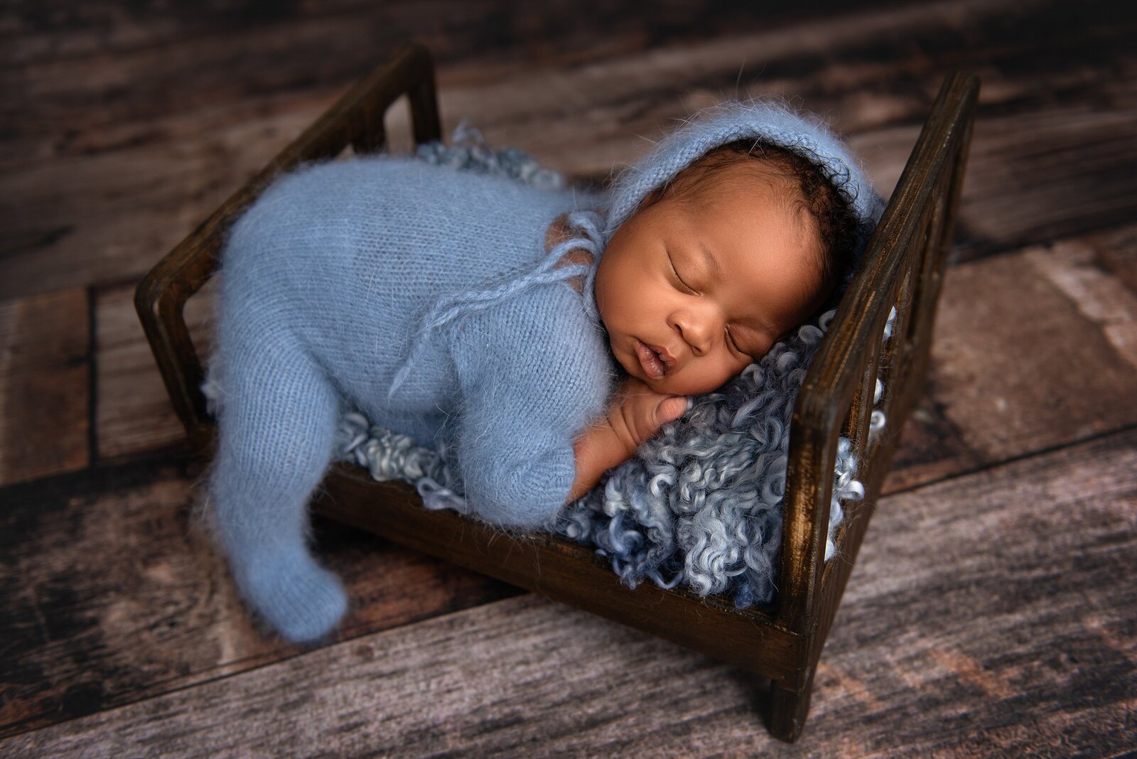 Best Wellington, FL Maternity and Newborn Photographer, Julie Logan, captures baby in a bed on a brown backdrop.