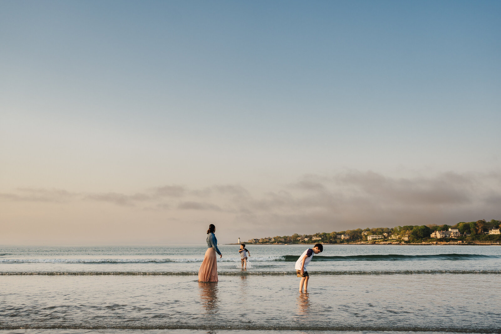 mom and suns walk in ocean at sunset