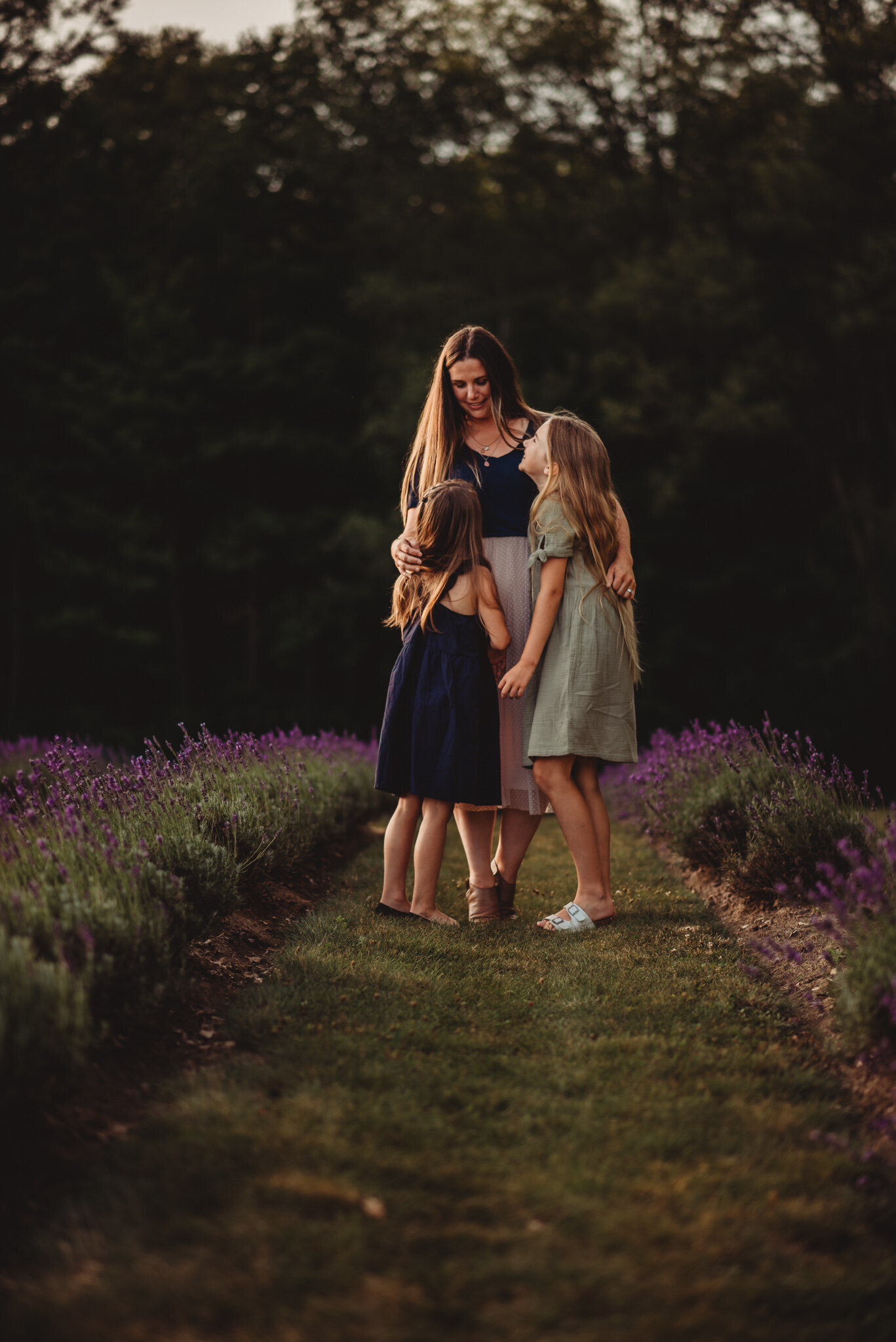 Mother hugging her two daughters in a lavender field