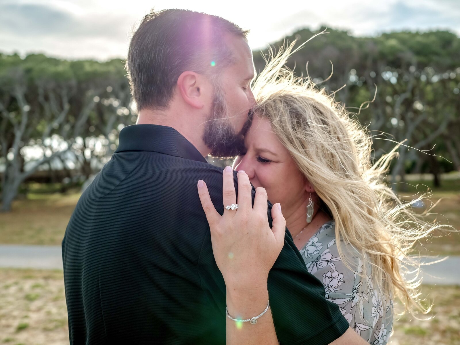 A tender moment as a couple embraces, with the man kissing the woman's forehead in Wilmington, NC. This image captures the authenticity and romance of wedding photography, perfect for those seeking heartfelt and genuine moments in their engagement photos.