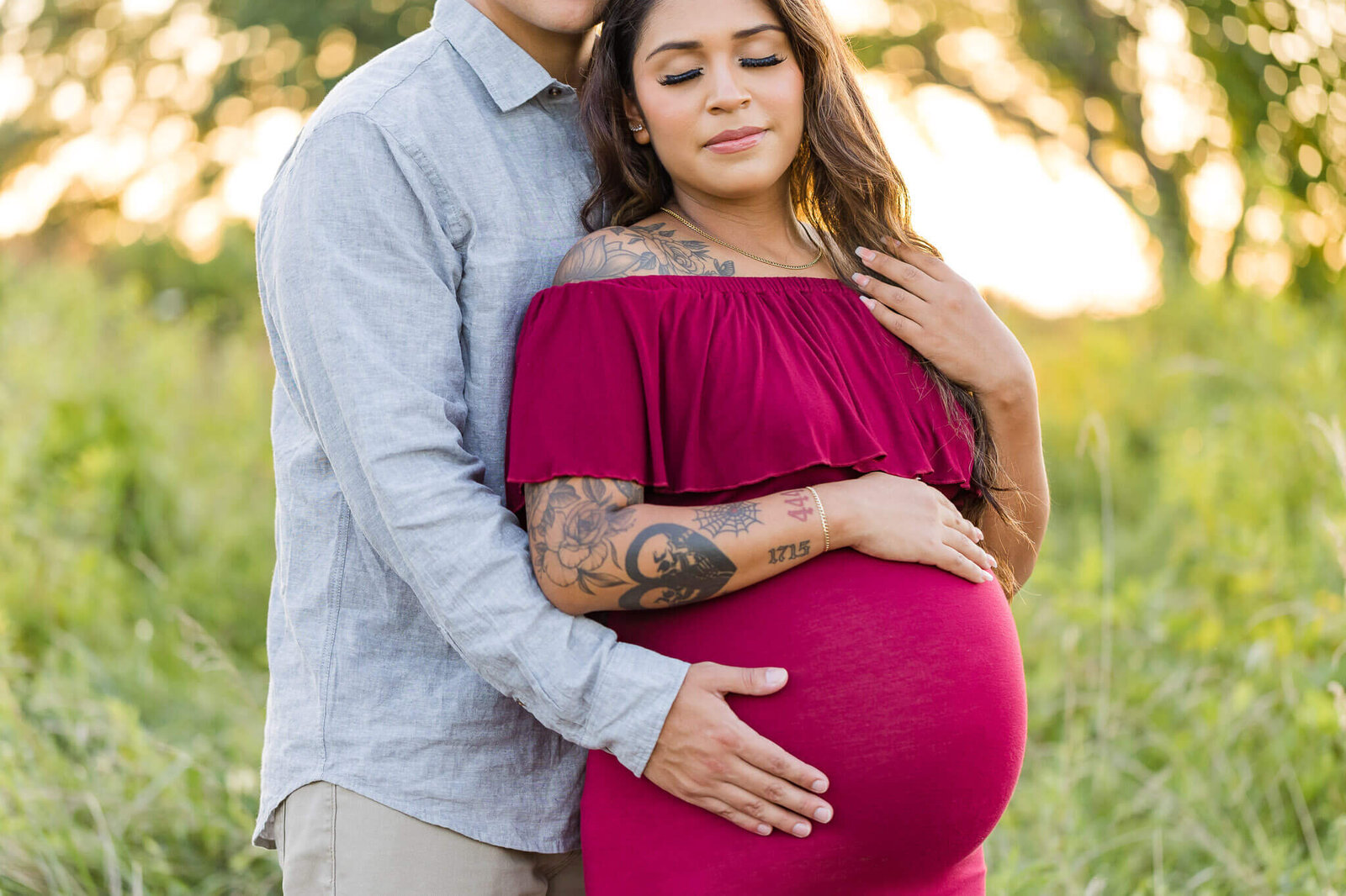 A couple expecting their first baby posing together at sunset.