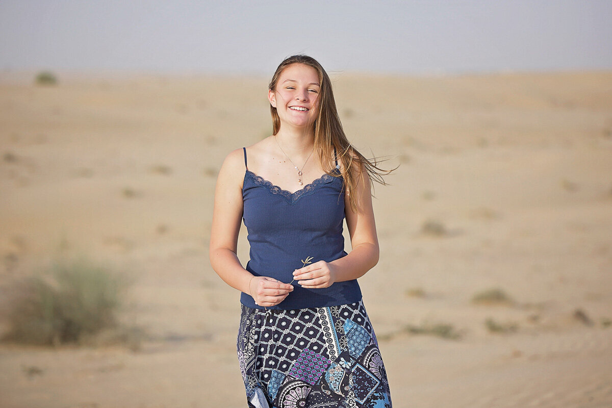 Young lady wearing blue skirt with prints and navy t-shirt in sands by Yuliia Terziian Photography