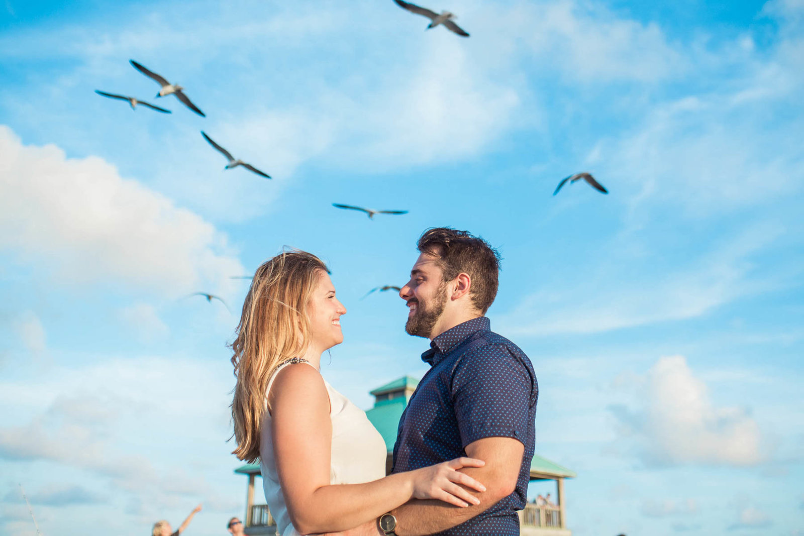 Engaged Couple has birds and blue skies above them, Folly beach in Charleston, South Carolina
