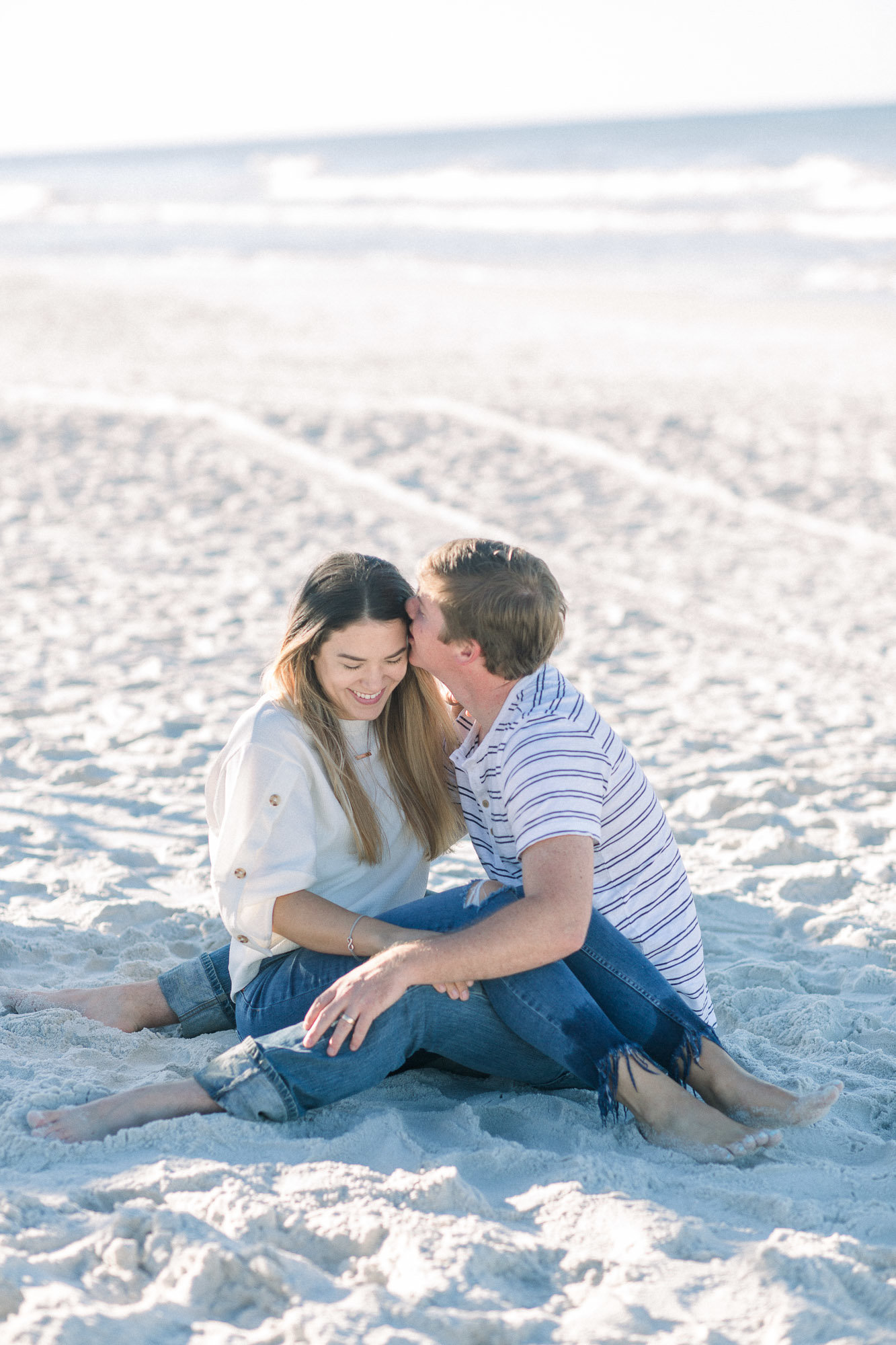Couple sitting on the beach captured by Staci Addison Photography