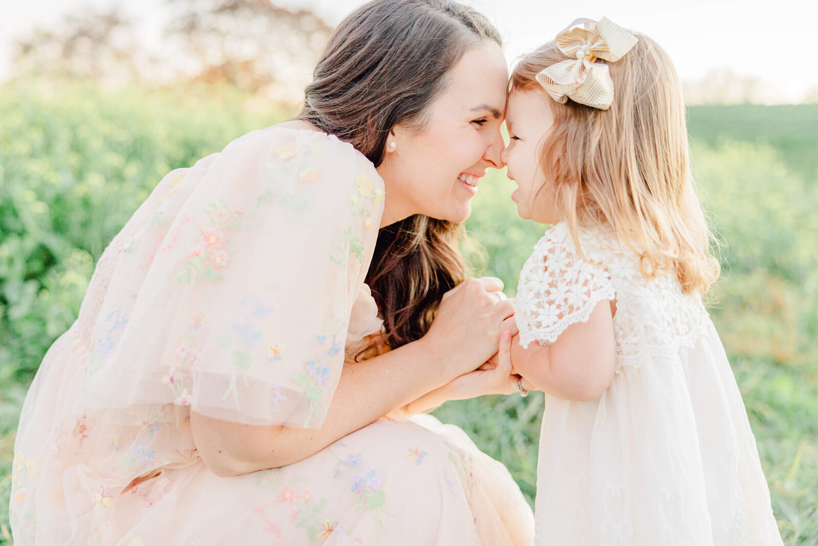 Mom squats down and laughs with her young daughter