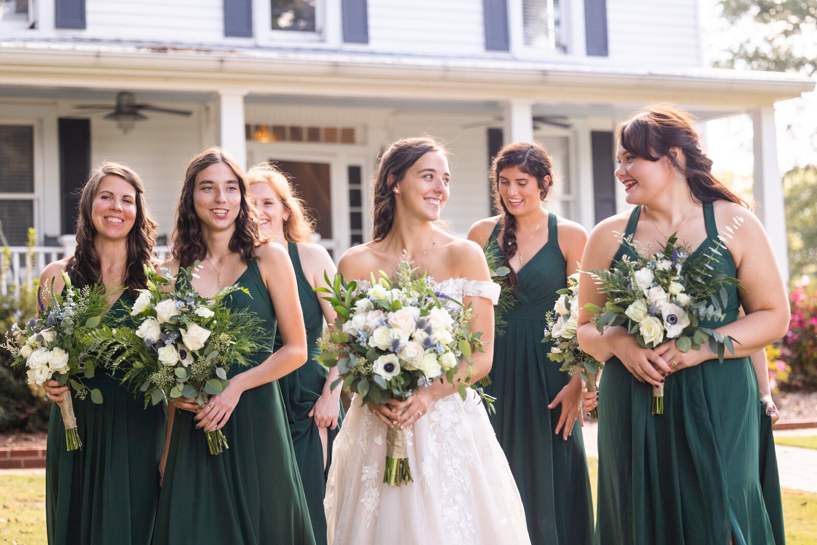 bride and bridesmaids smiling while walking and wearing green dresses at Correy House in Union Point Georgia by Georgia wedding photographer
