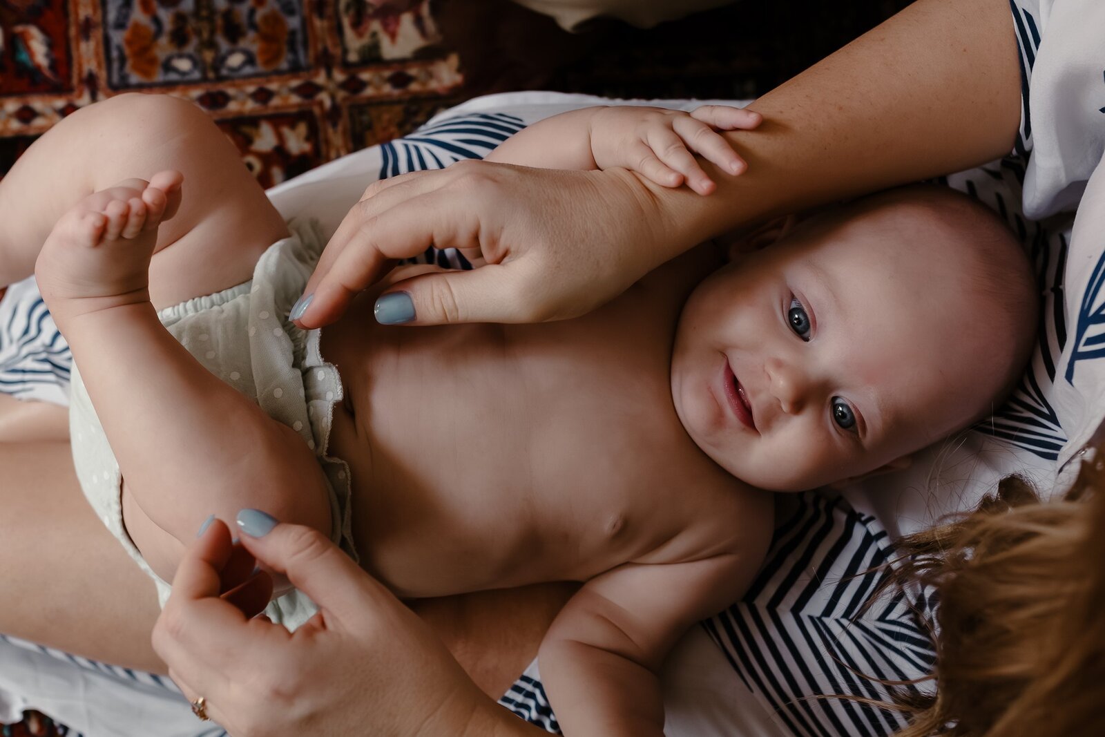 Newborn baby smiling laying down on mom's lap
