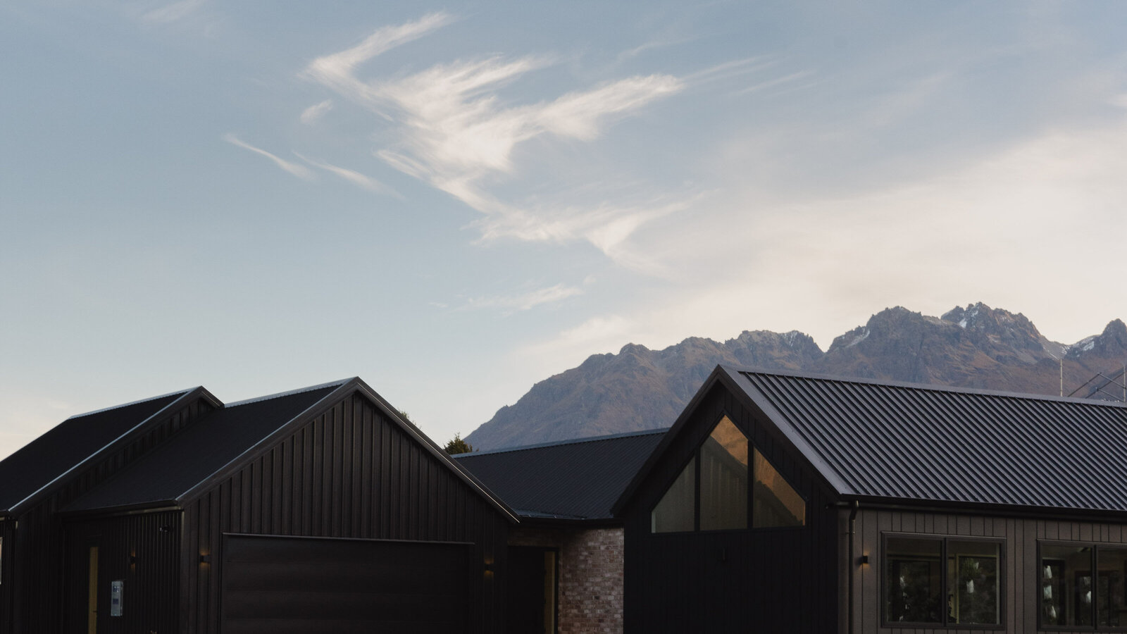The exterior of a home featuring timber cladding, brick features and James Hardie Oblique cladding on a home built by Twin Peaks Construction in Hanleys Farm, Queenstown.