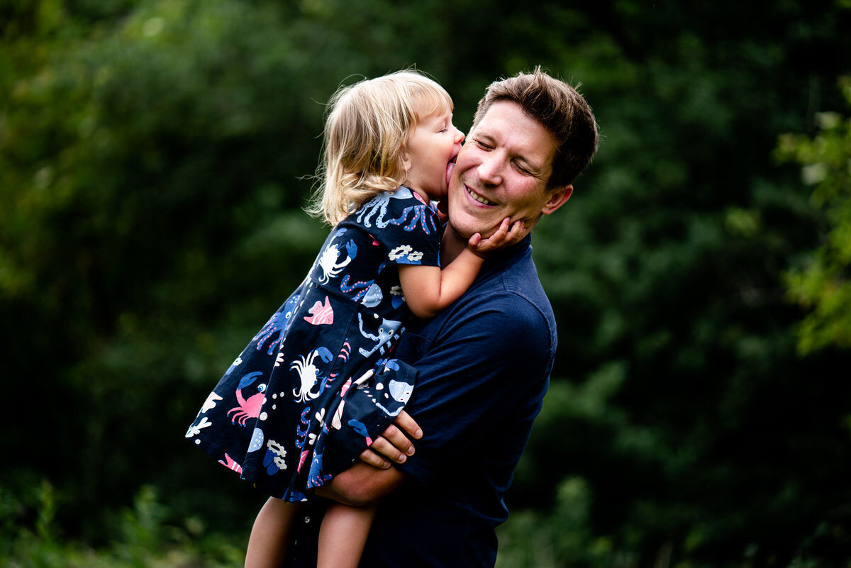 dad holding daughter during portrait shoot whilst she licks his cheek