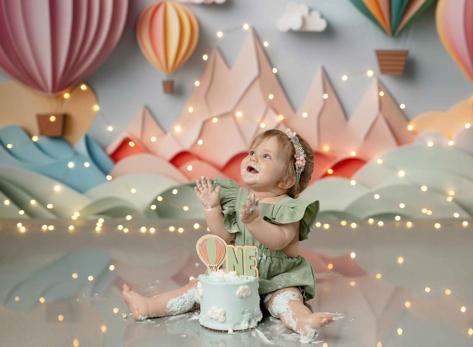 Baby girl eating birthday cake and looking at mom and clapping with big smile. 1st birthday photo taken in Atlanta by Jenni Nikki Photography.