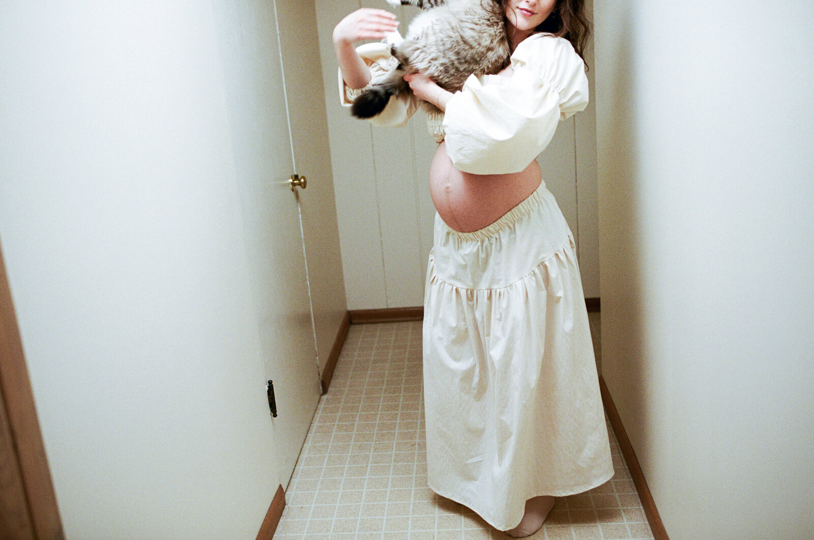 Pregnant mother holding cat in hallways in her Portland, Oregon home.