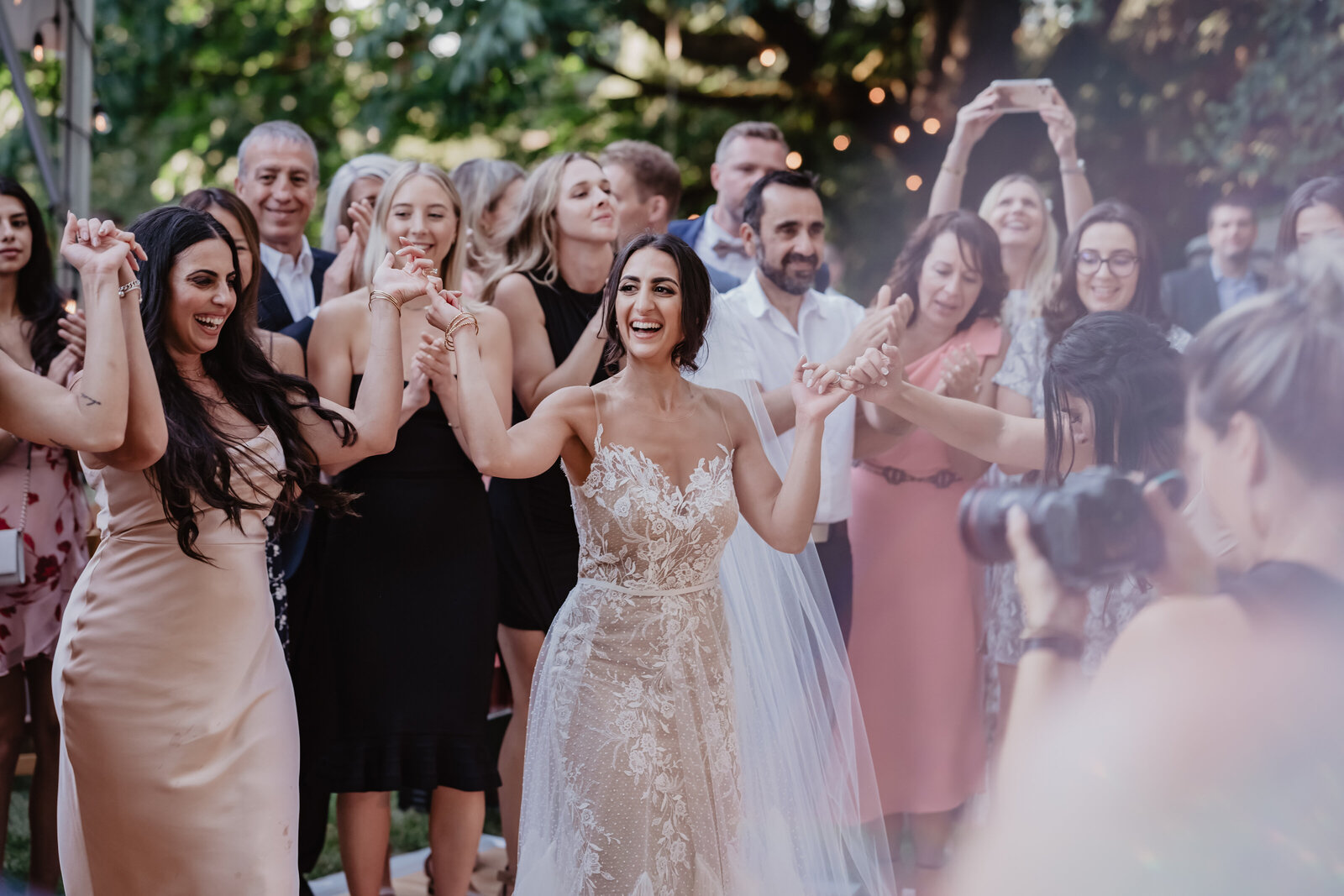Bride dancing with her mom and sister during cocktail hour, celebrating together in the daylight.