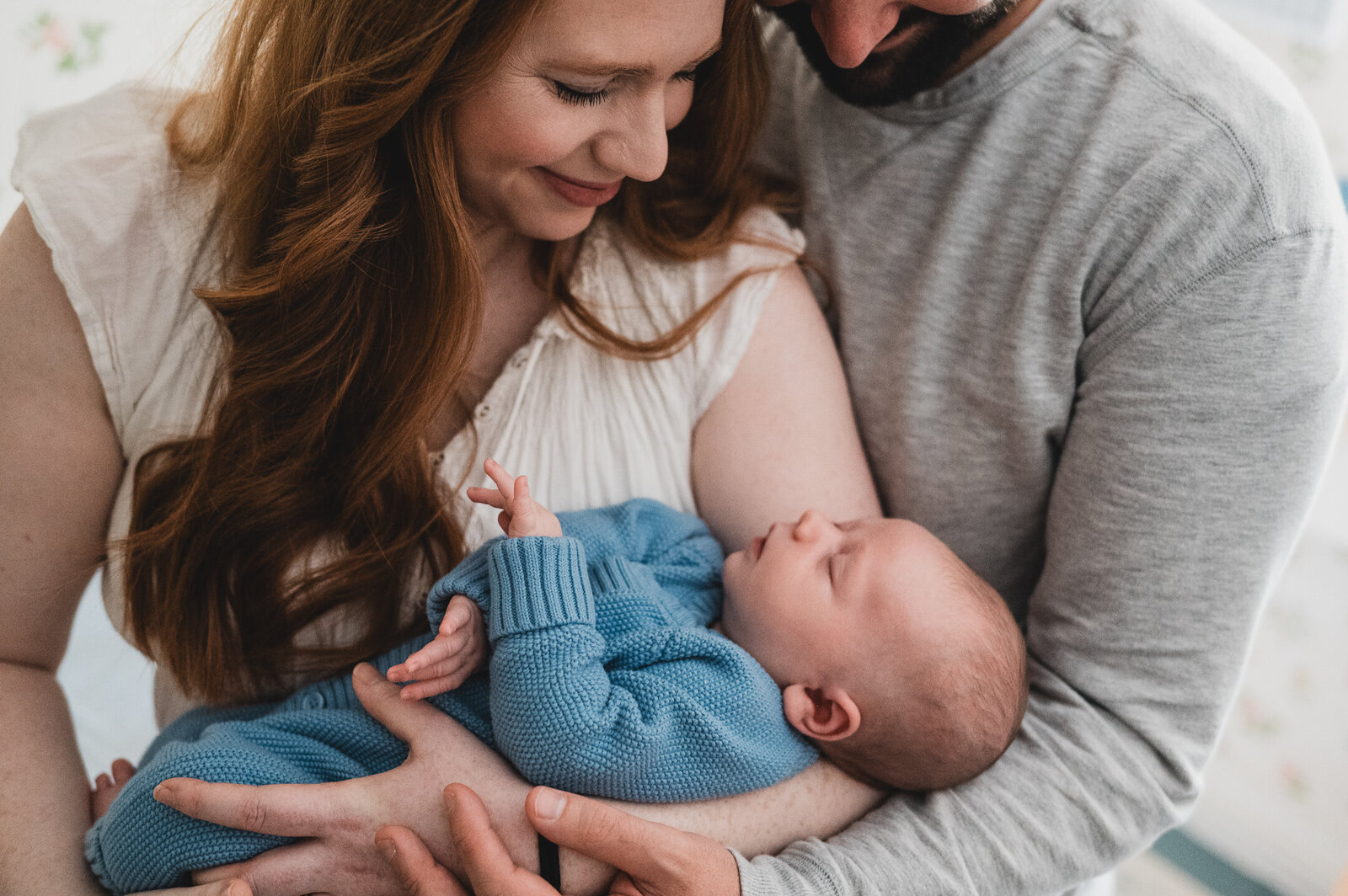 Parents and dog gathered in the nursery as father holds newborn and mother smiles down at the dog