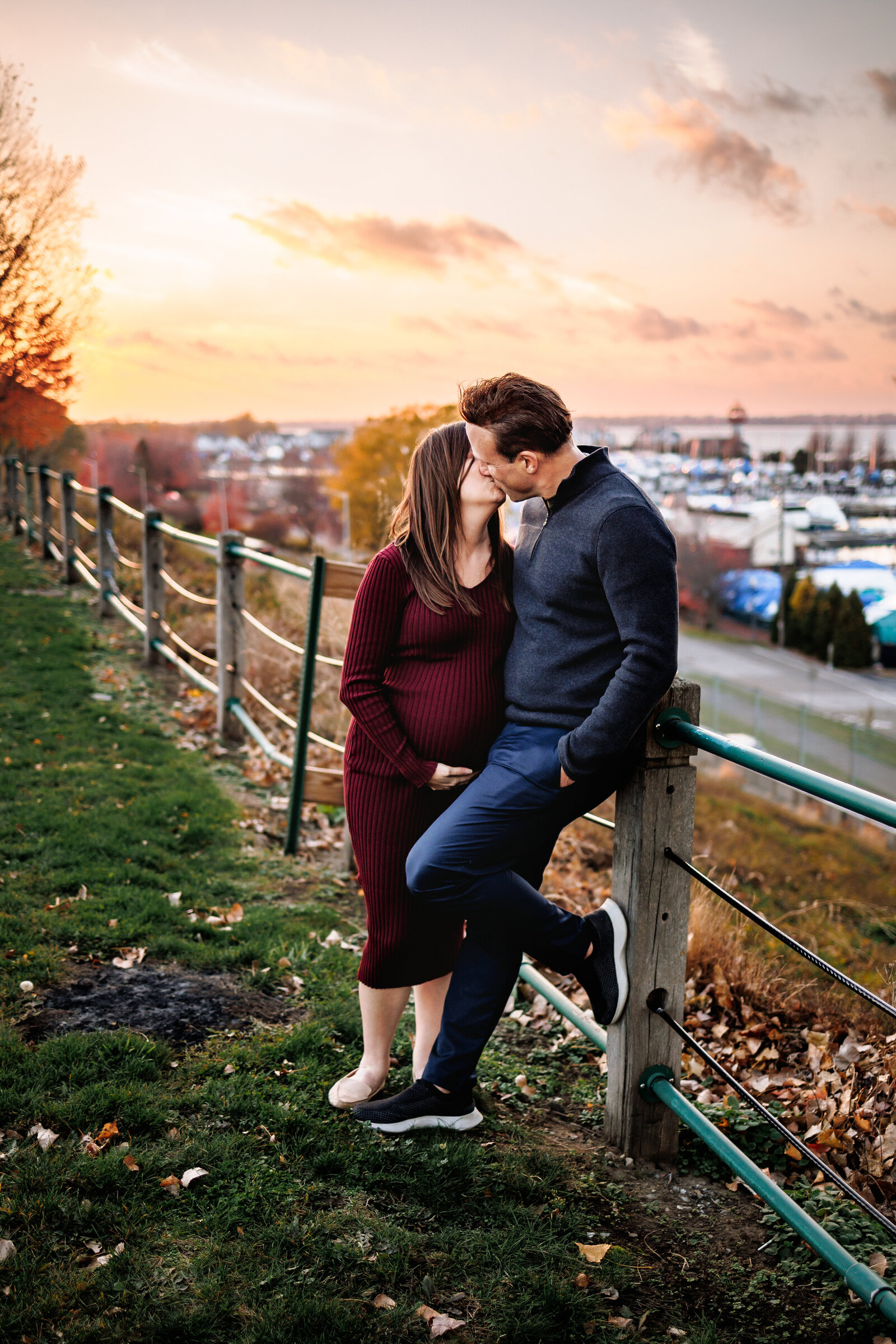 Expecting couple stands together against a backdrop of a beautiful lake Erie susnet