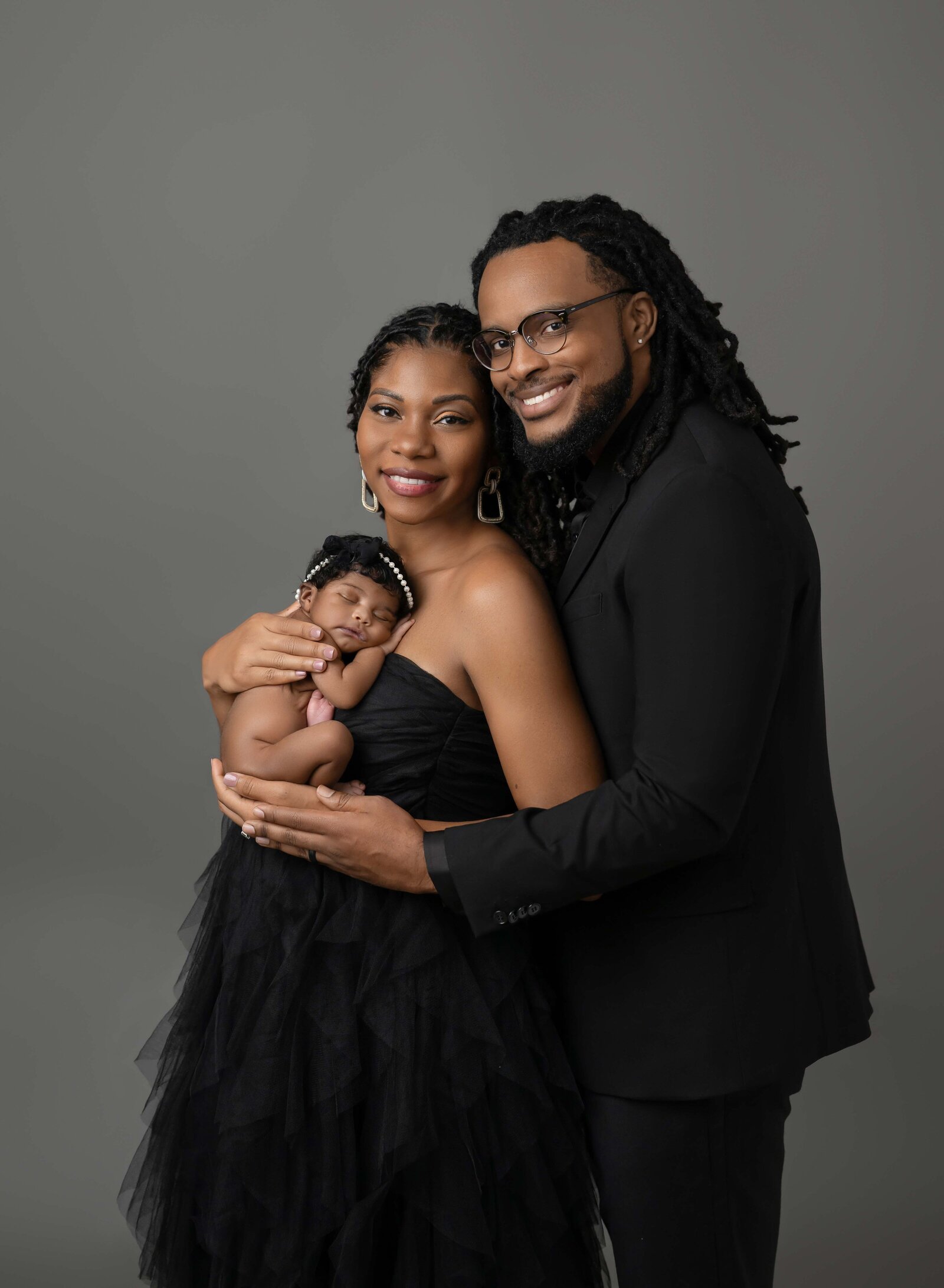 Family of 3 with newborn baby girl taking professional photo at Marietta Photo Studio. Baby is naked and sleeping on mom's chest and Dad and hugging Mom. Newborn Photography in Atlanta GA by Jenni Nikki Photography.