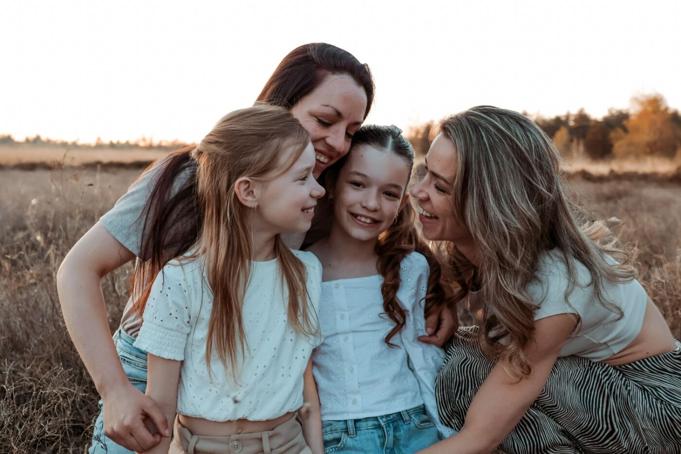 Vrolijke familieportret van moeder en dochters tijdens fotosessie in avondlicht