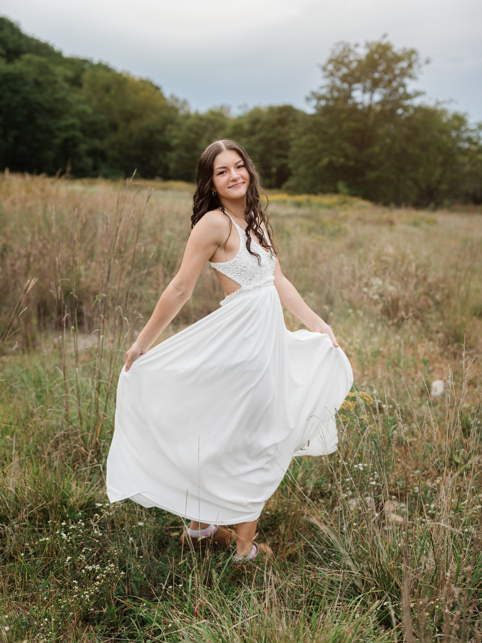 senior girl in white dress posing in field for senior portraits cleveland senior phototographer