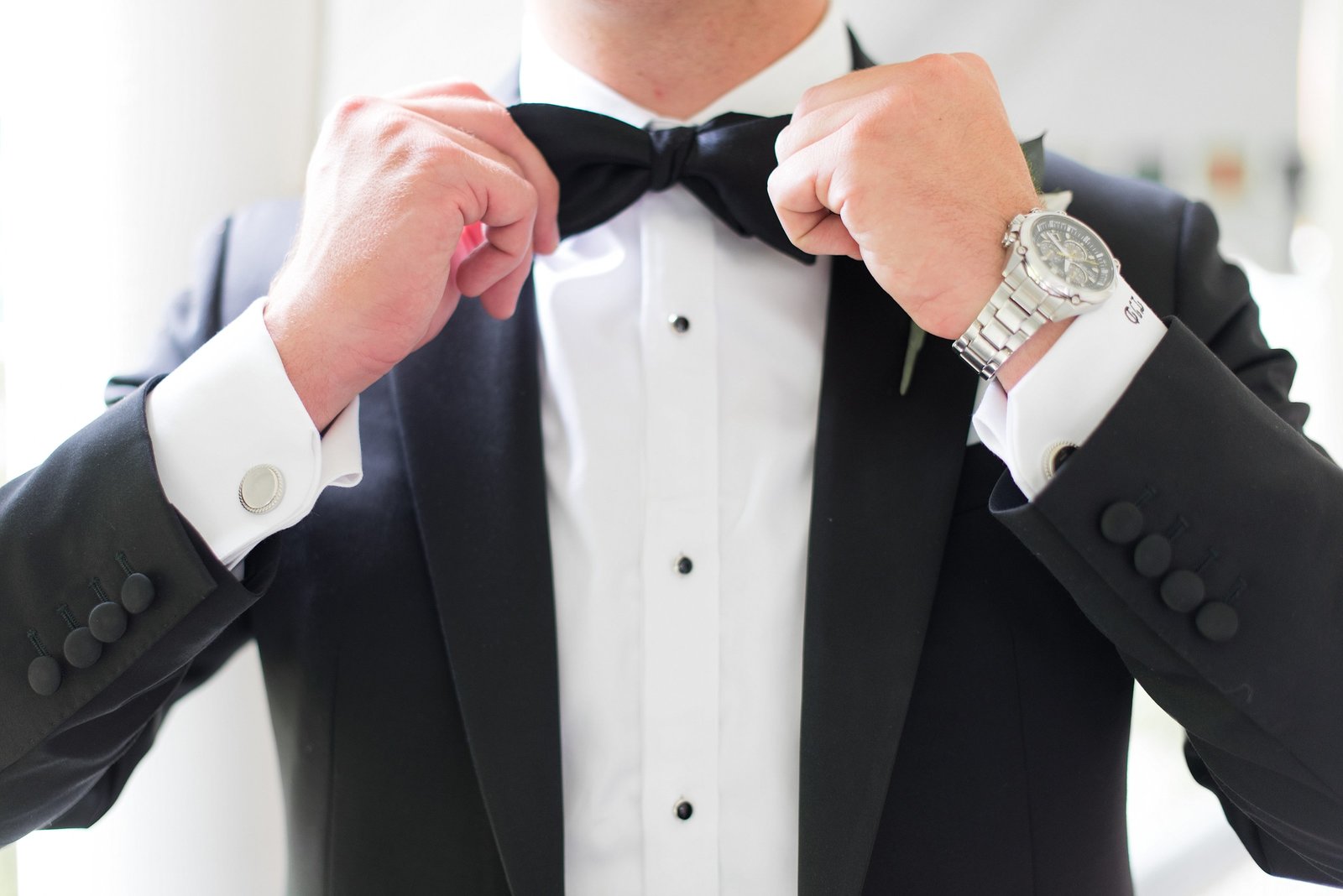 Classic Photo of Groom getting ready in a black tuxedo and fixing his bow tie
