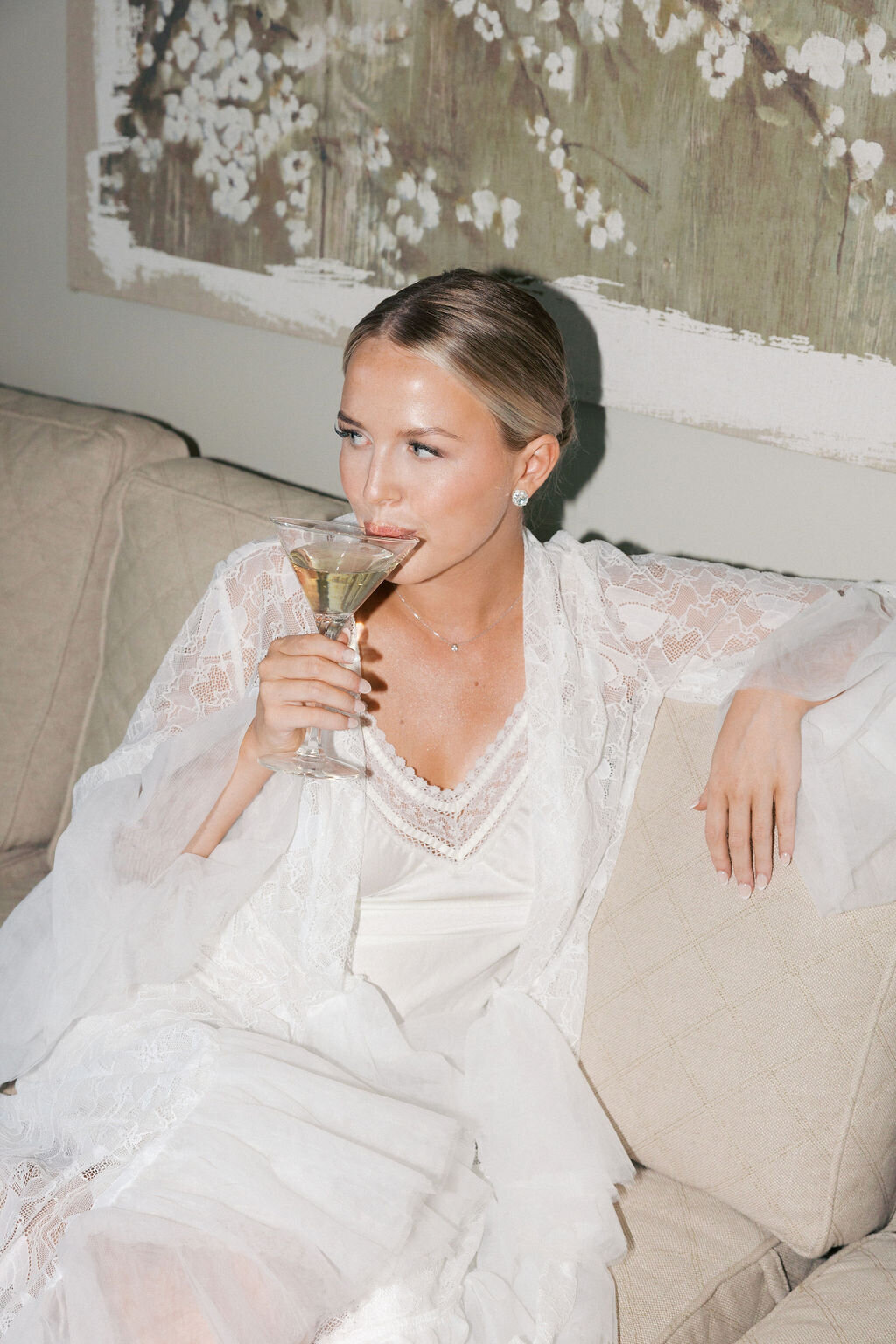 Bride sips from martini glass getting ready for wedding day