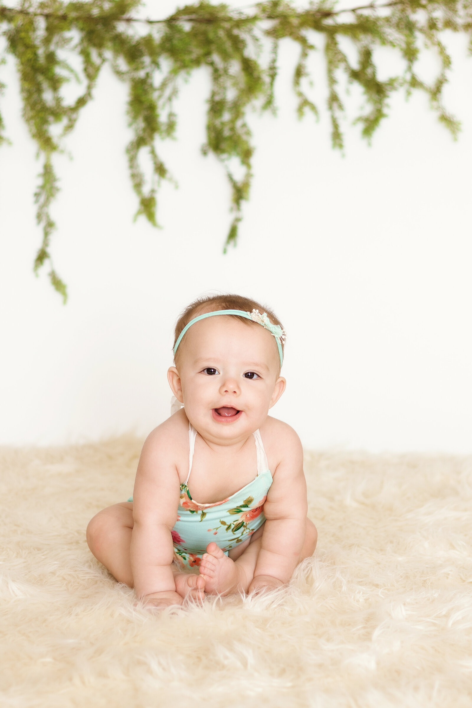 Milestone Photographer, a baby  sits up on carpet wearing her swimsuit`