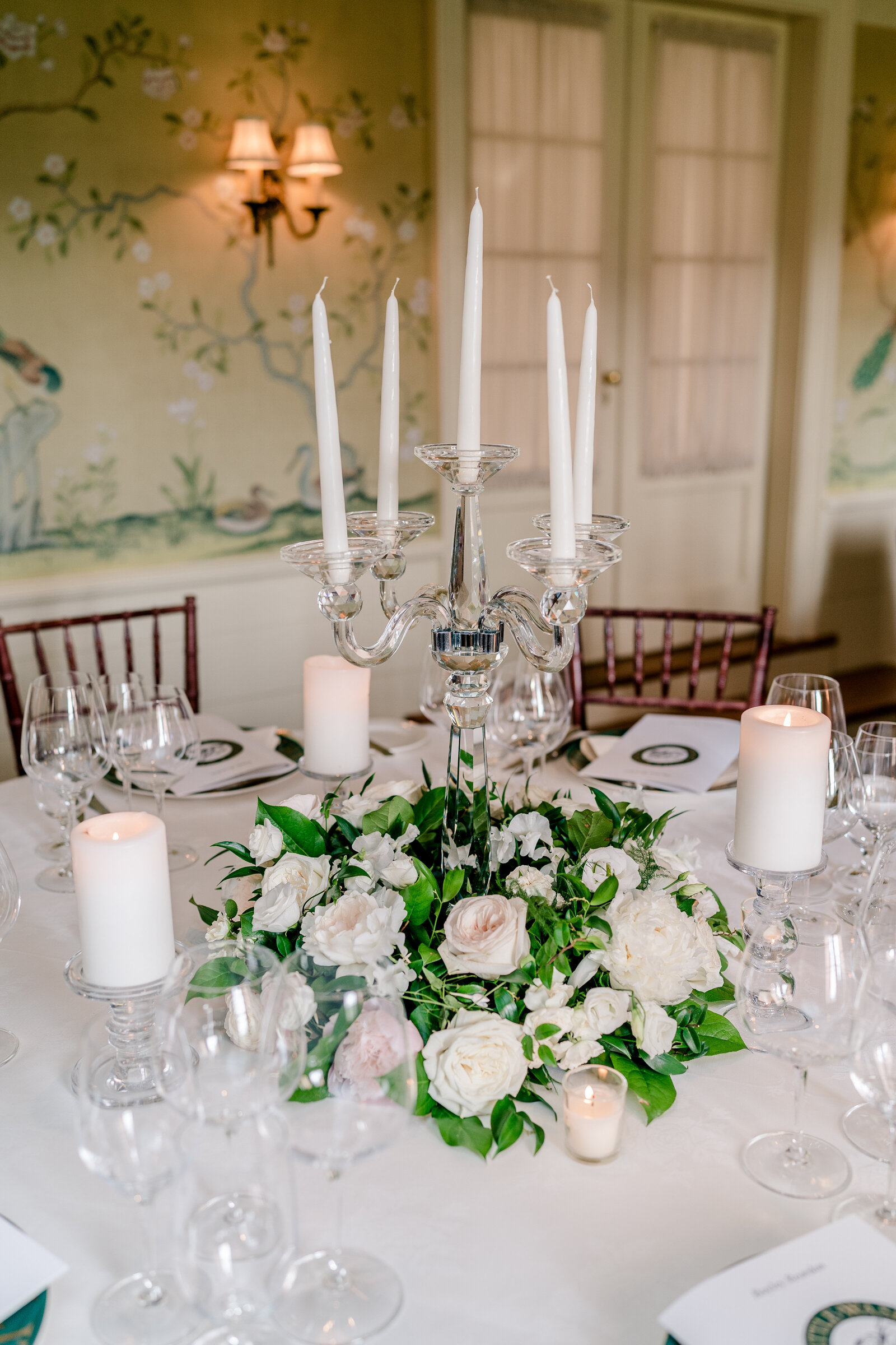 A glass candelabra surrounded by white roses decorating a wedding at The Inn at Little Washington in Virginia
