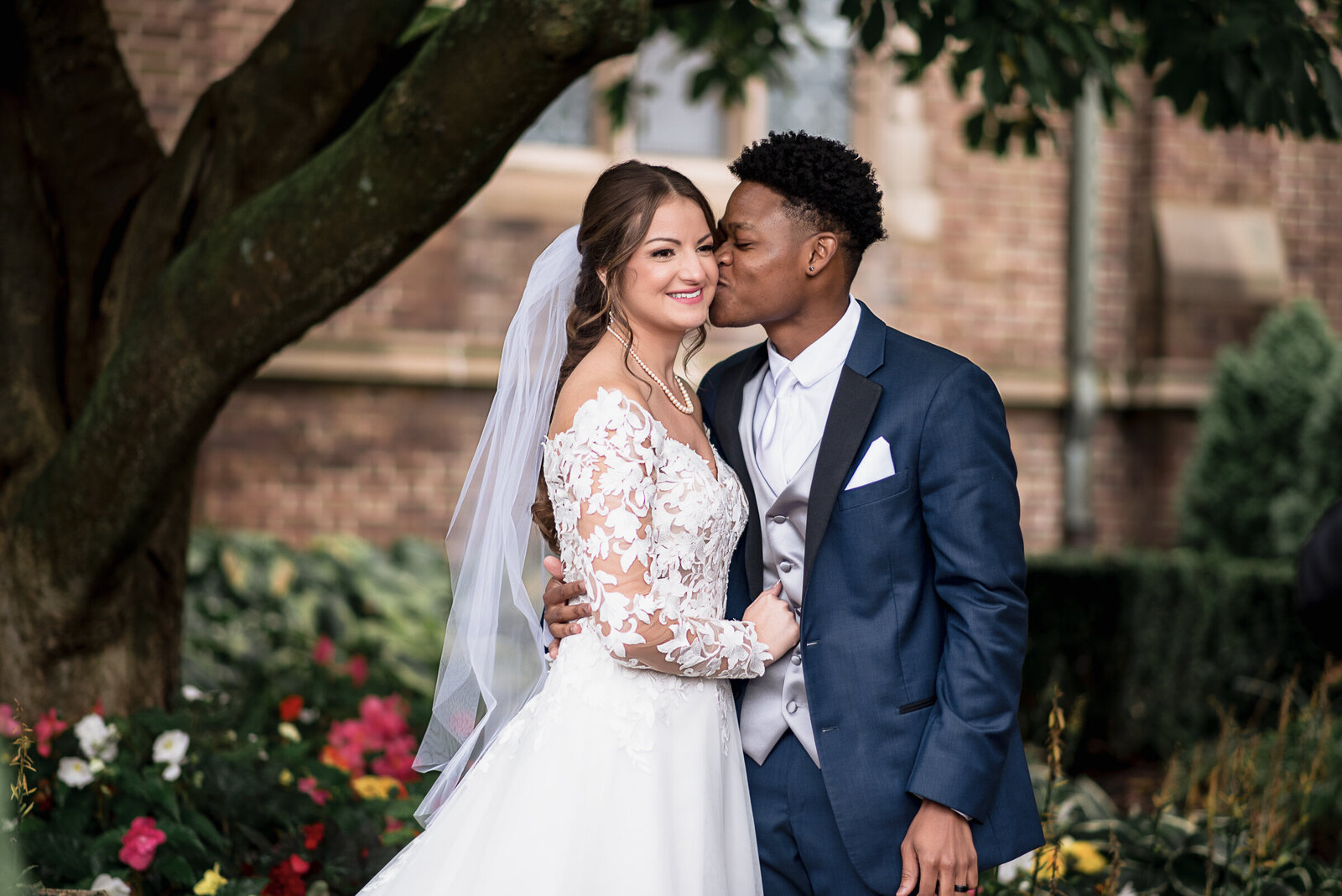 Man kisses wife on cheek during their wedding photos
