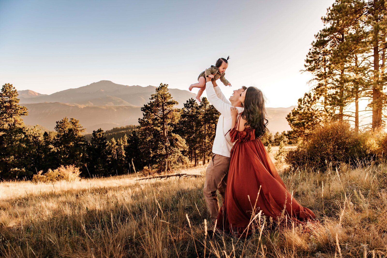 Family walking up red rock formations at Garden of the Gods in Colorado Springs with Pikes Peak in the background