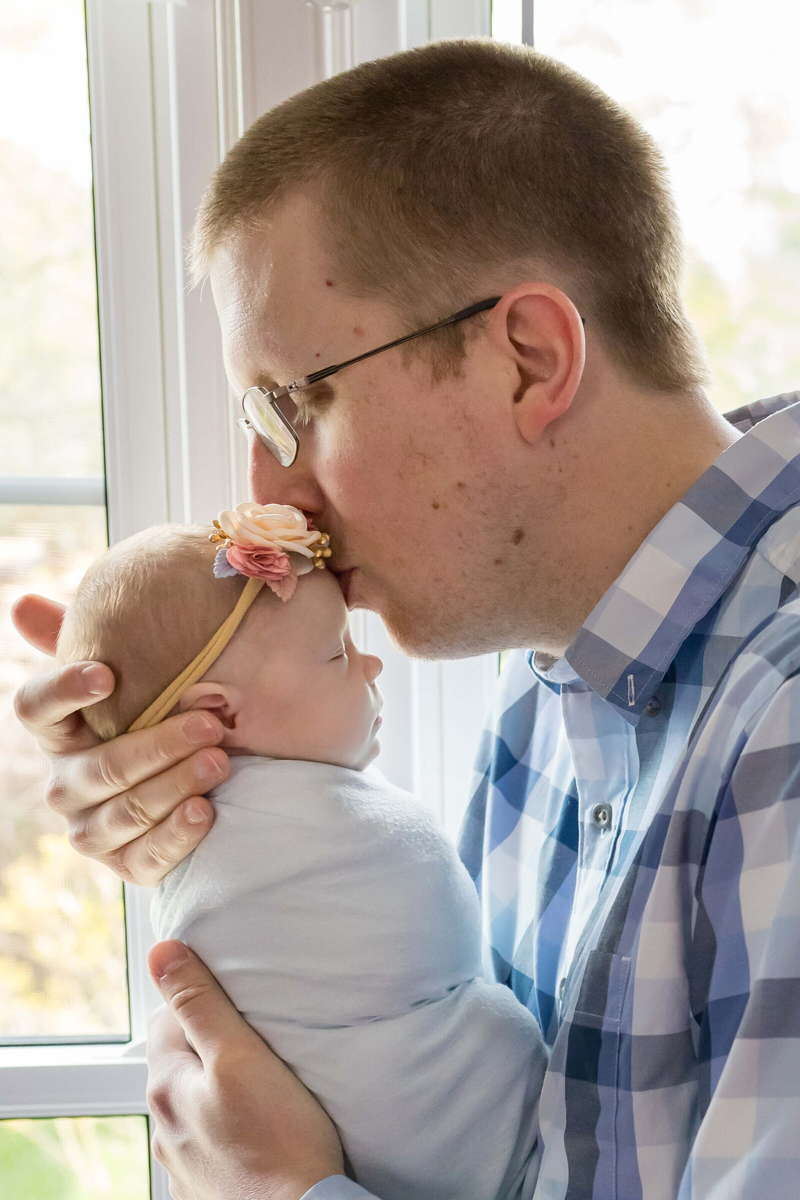 A dad kissing his newborn girl's forehead in their home in Manassas.
