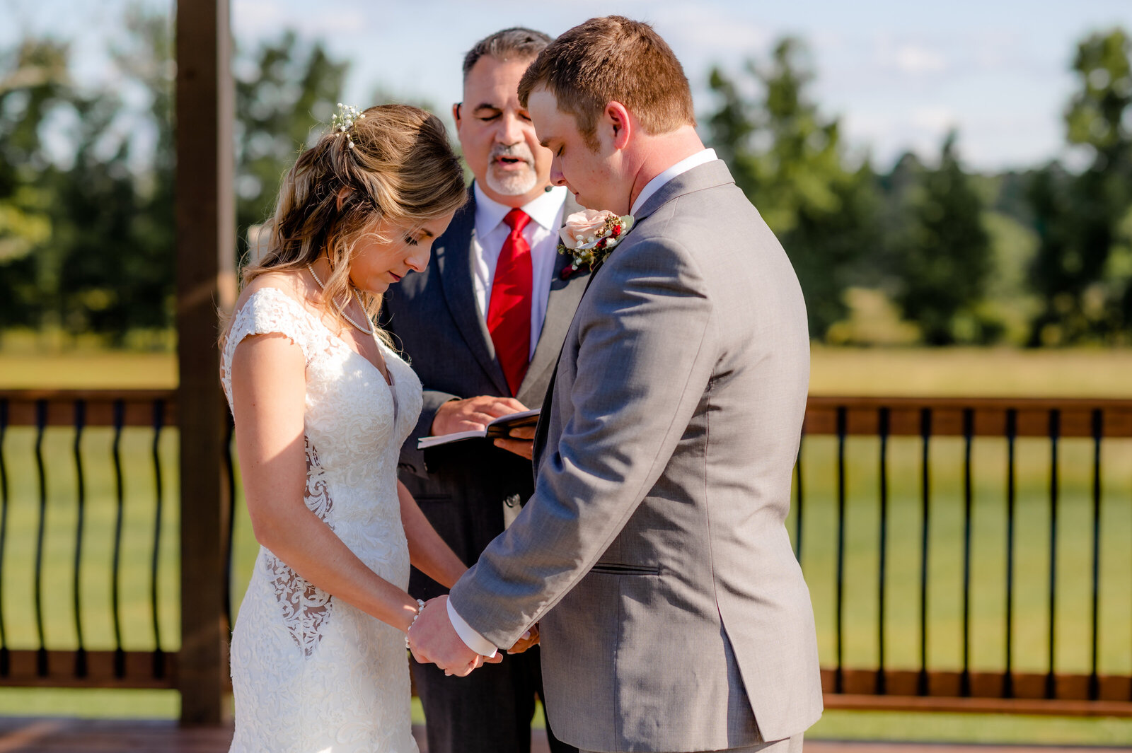 outdoor wedding ceremony with bride and groom holding hands and bowing their heads during their little rock wedding ceremony