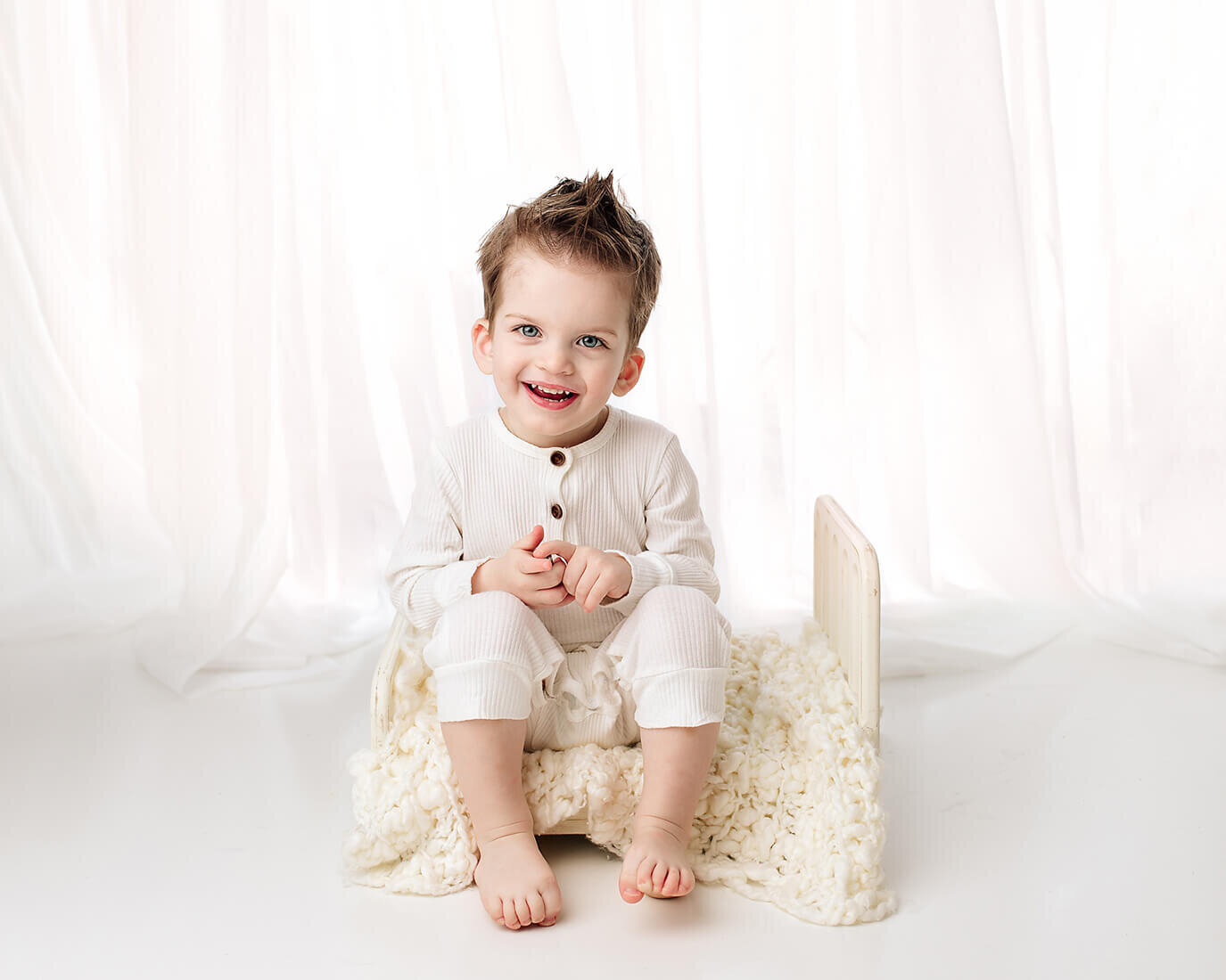 boy smiling on bed with white set up
