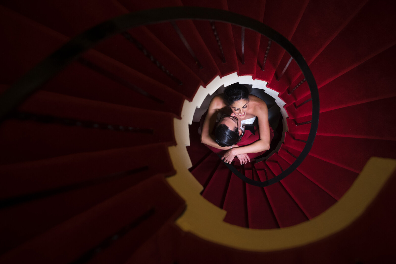 Bride and groom on their wedding day pose on the Addison's red spiral staircase