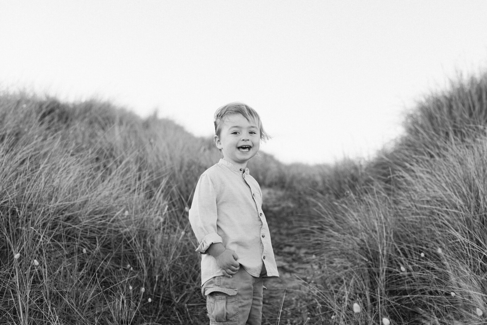 a little boy smiling in the dunes at a family photoshoot in billingshurst