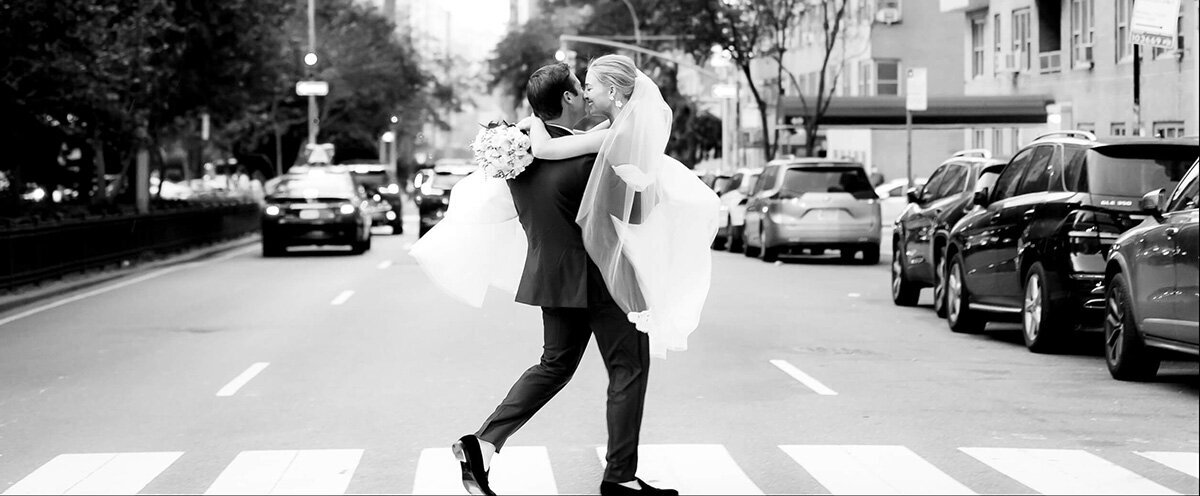 groom carrying bride across Park Ave in NYC