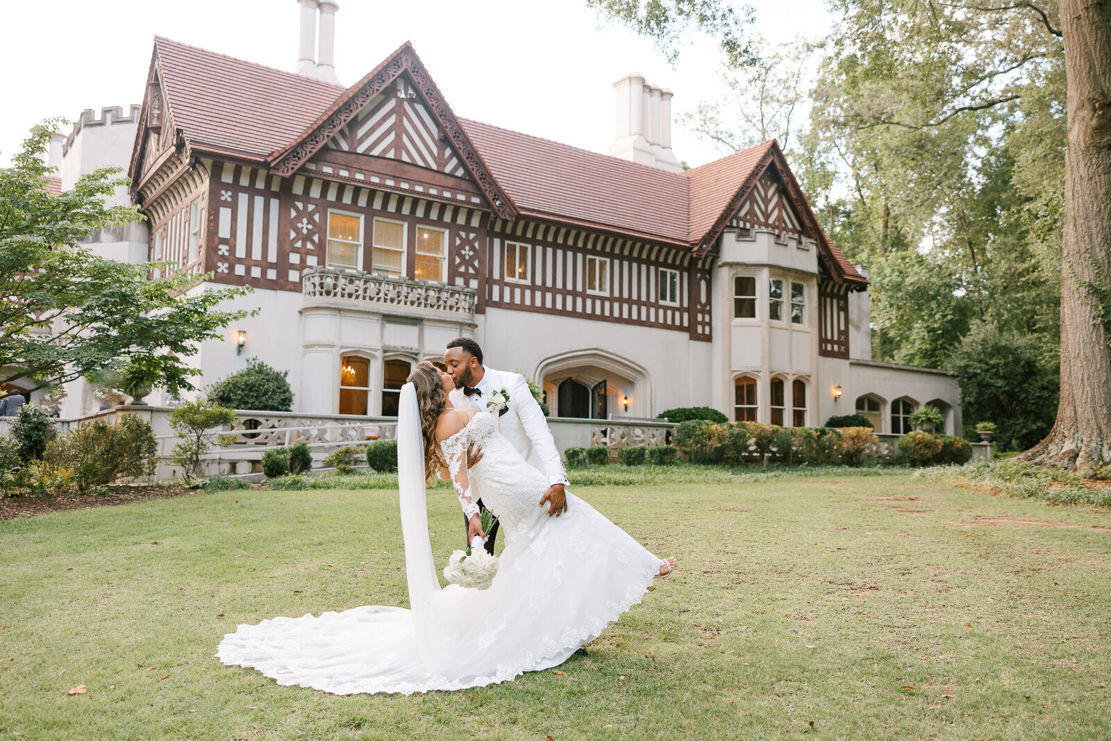 bride and groom dip kiss wearing all white in front of callanwolde fine arts center lawn atlanta venue for weddings