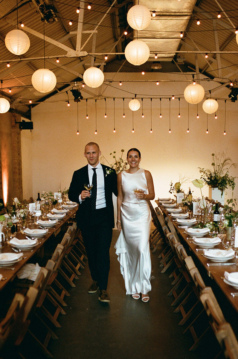 bride and groom posing between tables at shoreditch studios captured on 35mm film by london film wedding photographer
