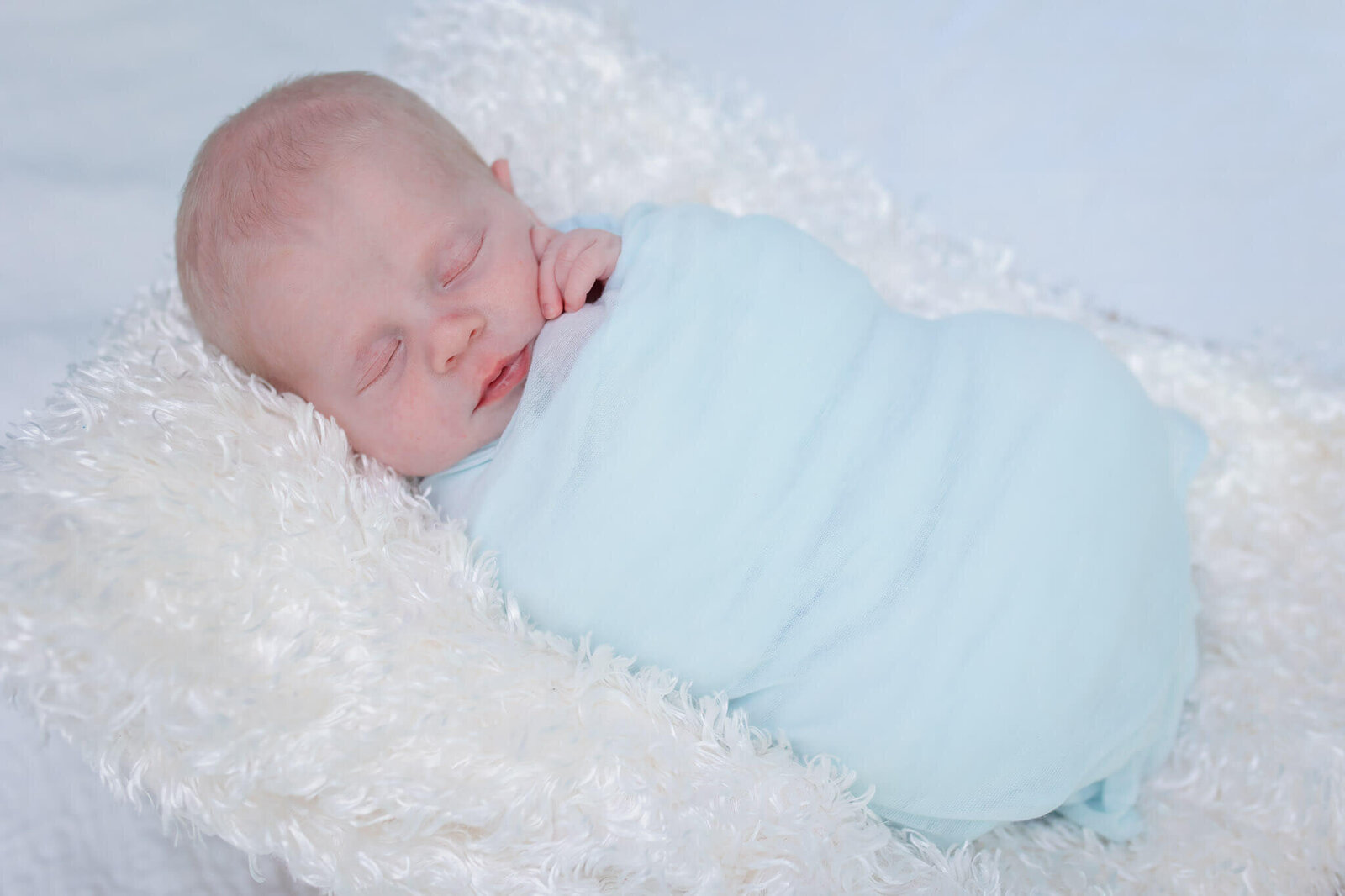 A sleeping newborn wrapped in blue.