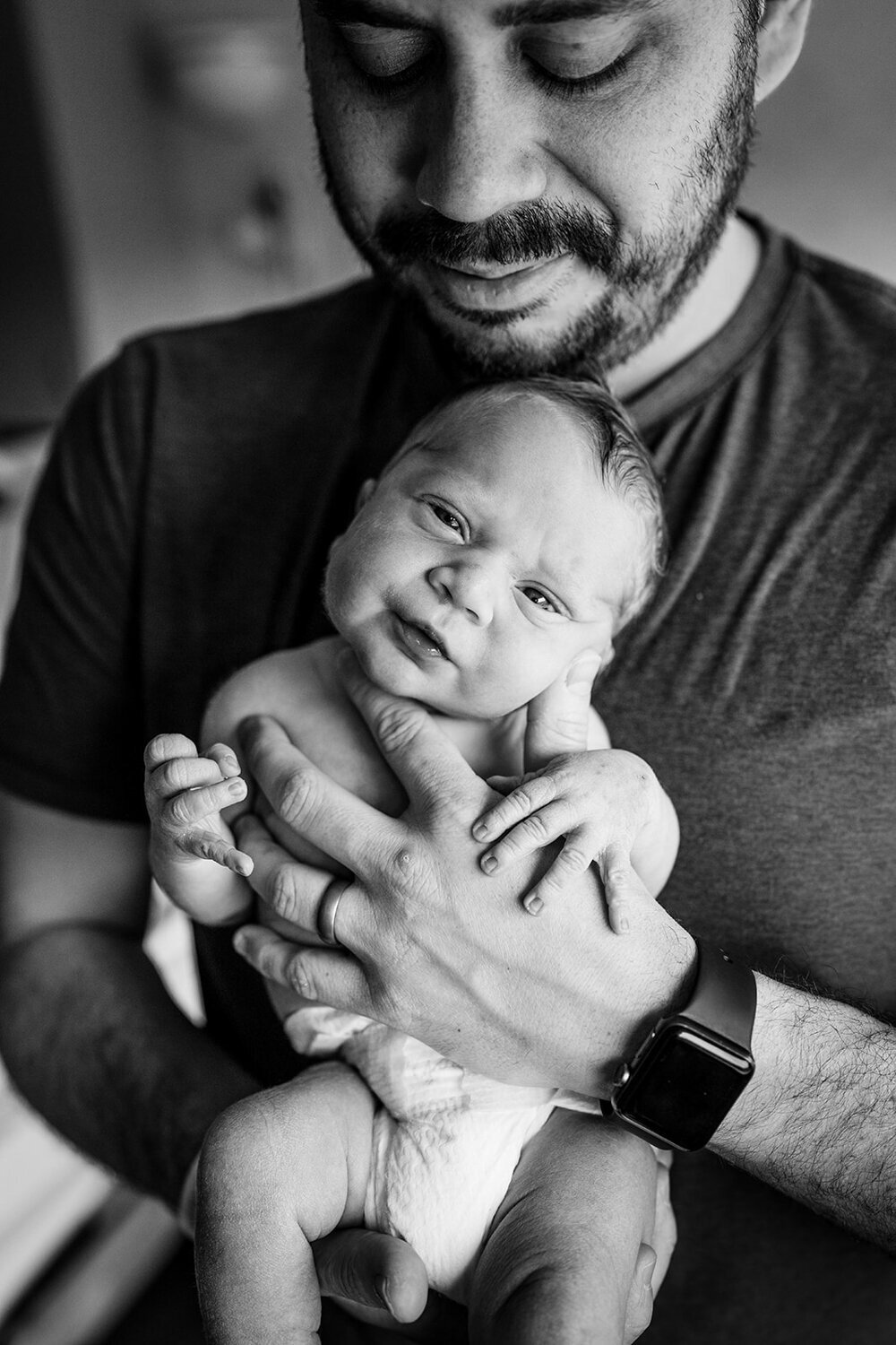 black and white portrait of dad holding baby boy in hospital