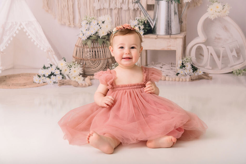 Portrait Photographers CT capture adorable baby girl in coral pink tulle dress during first birthday photoshoot