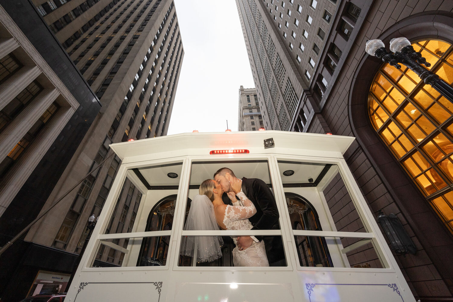 A bride and groom kissing on a trolley in the city
