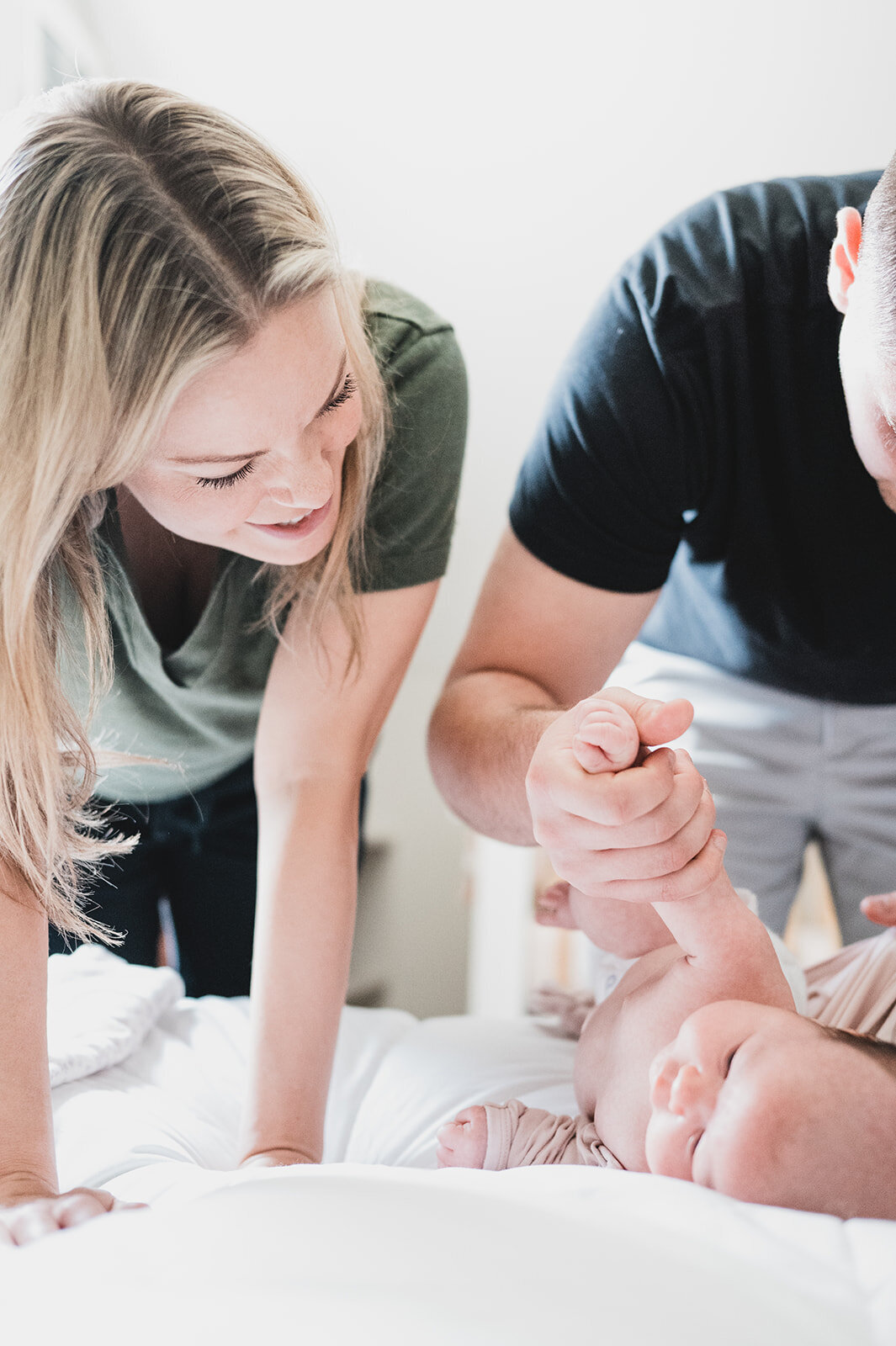 Candid moment of two parents gently dressing their newborn on the bed
