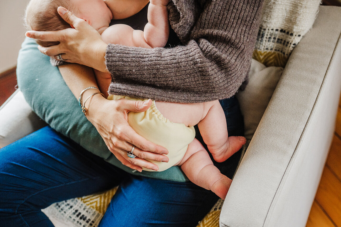 mom nurses baby in cloth diaper in rocking chair