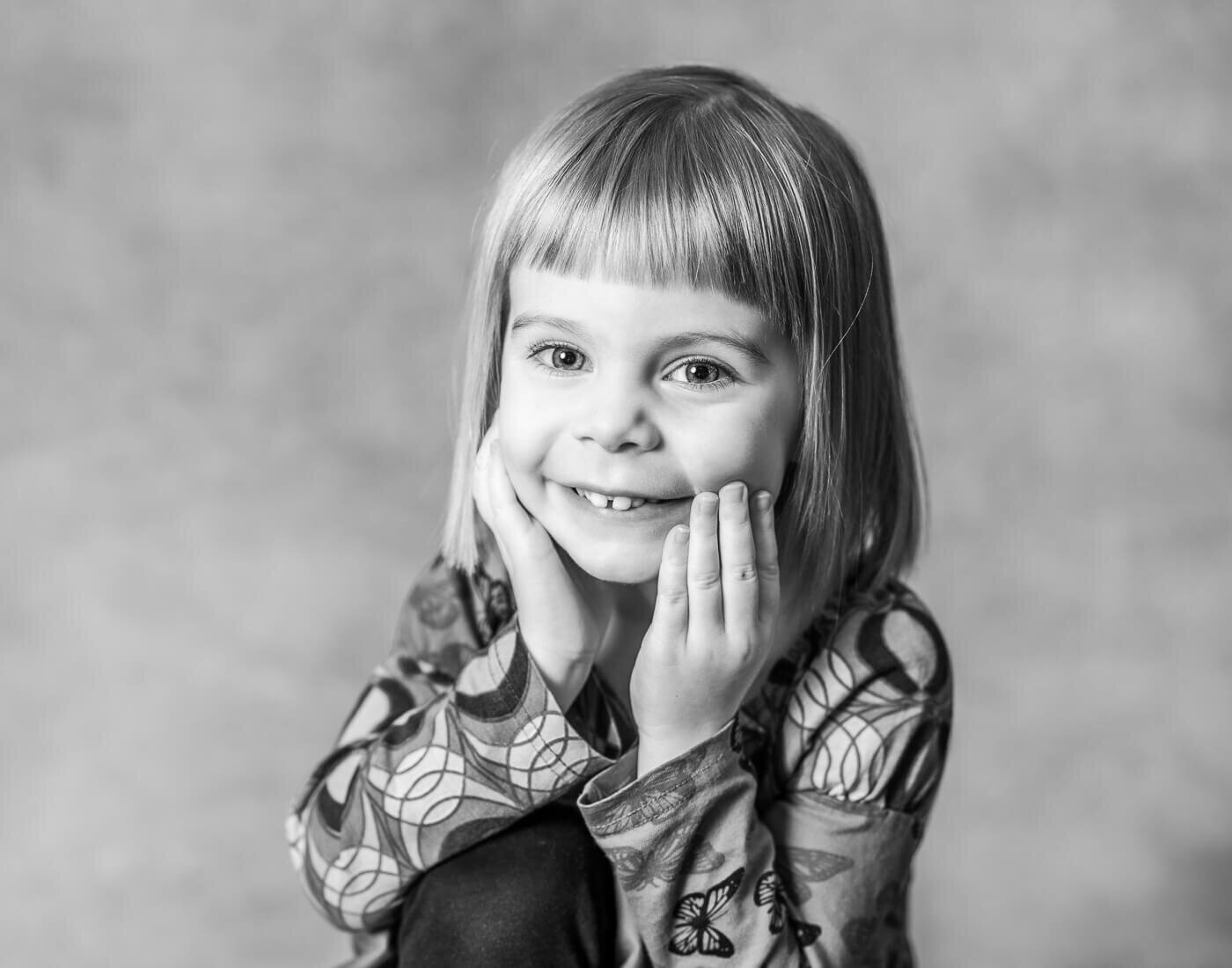 A young girl smiles with her hands on her dimples.