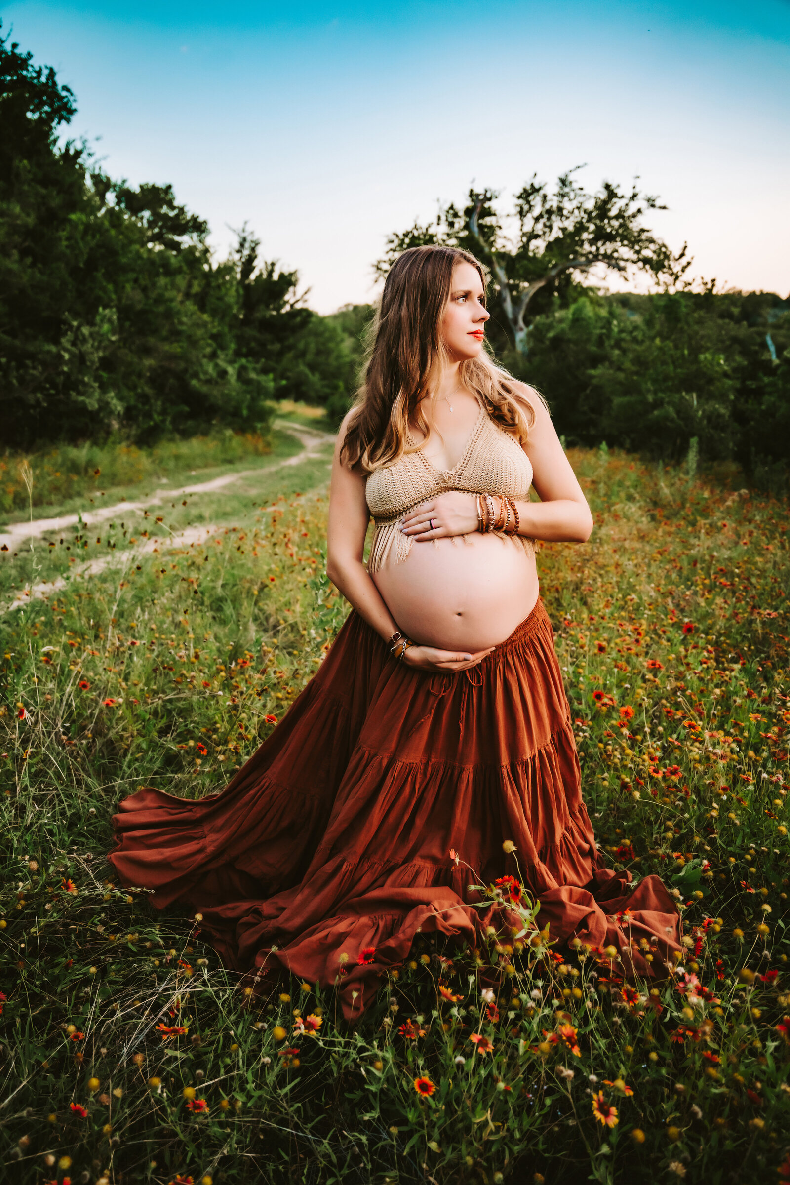 Maternity Photographer, an expectant mother stands in a flower field in a skirt