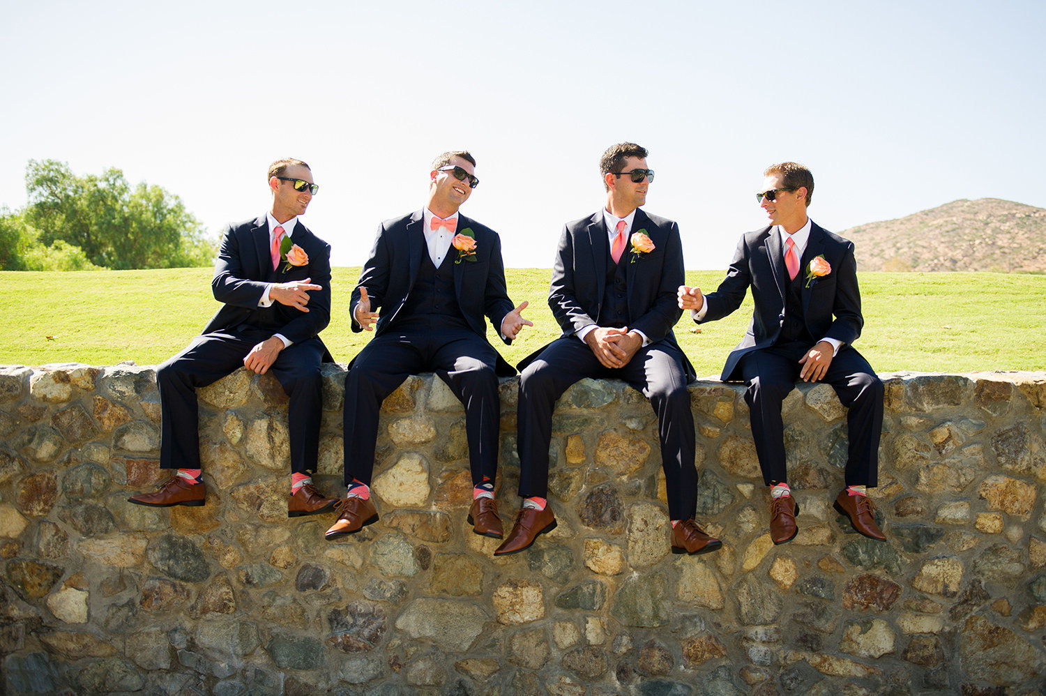 groomsman sitting on the wall laughing