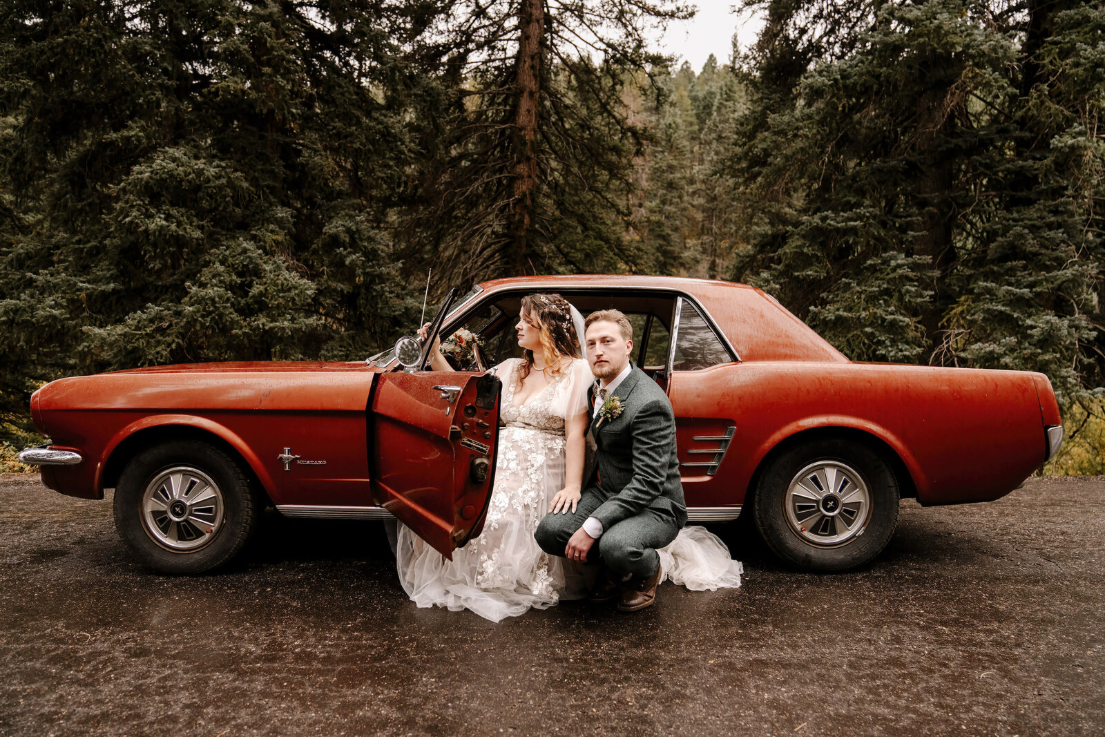 bride and groom by red car