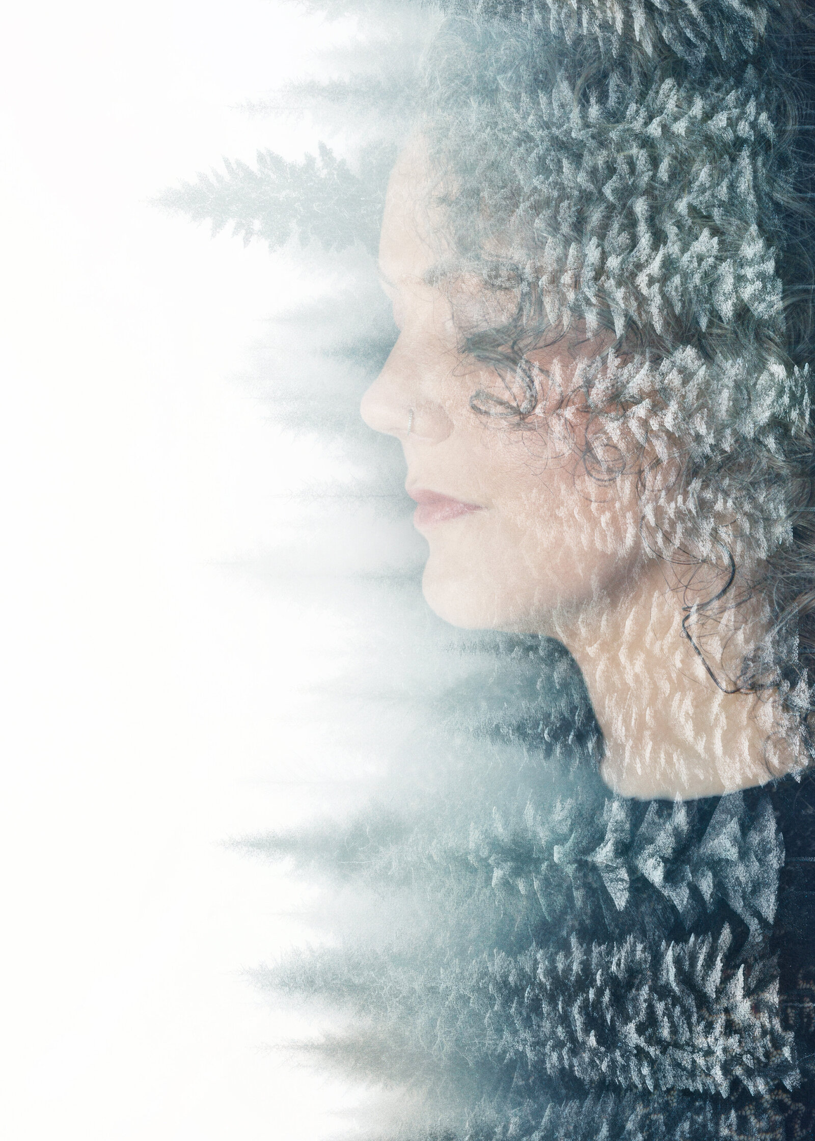 Double exposure of woman's profile and evergreen trees.